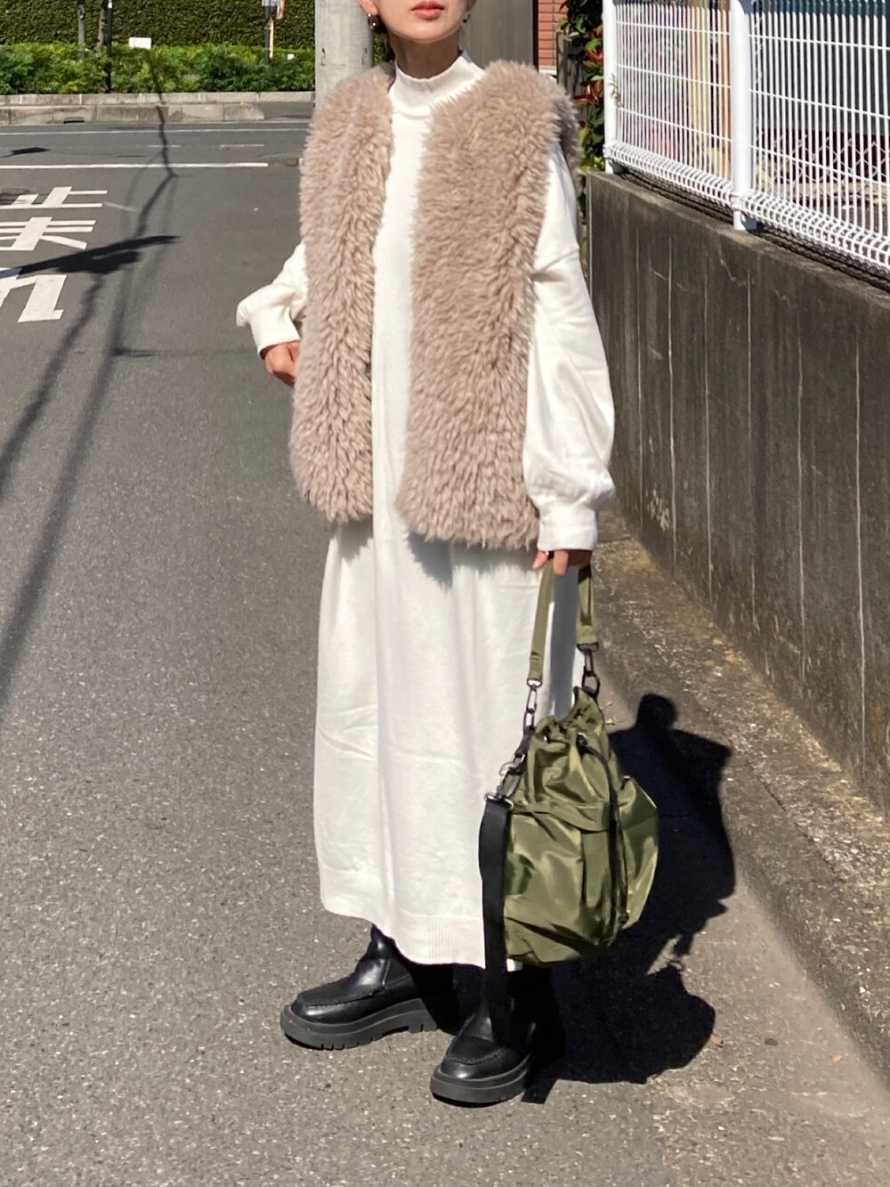 ホワイト系のワンピース、ベージュ系のベスト、グリーン系のショルダーバッグを着用したレディースの秋コーディネートの4枚目の写真