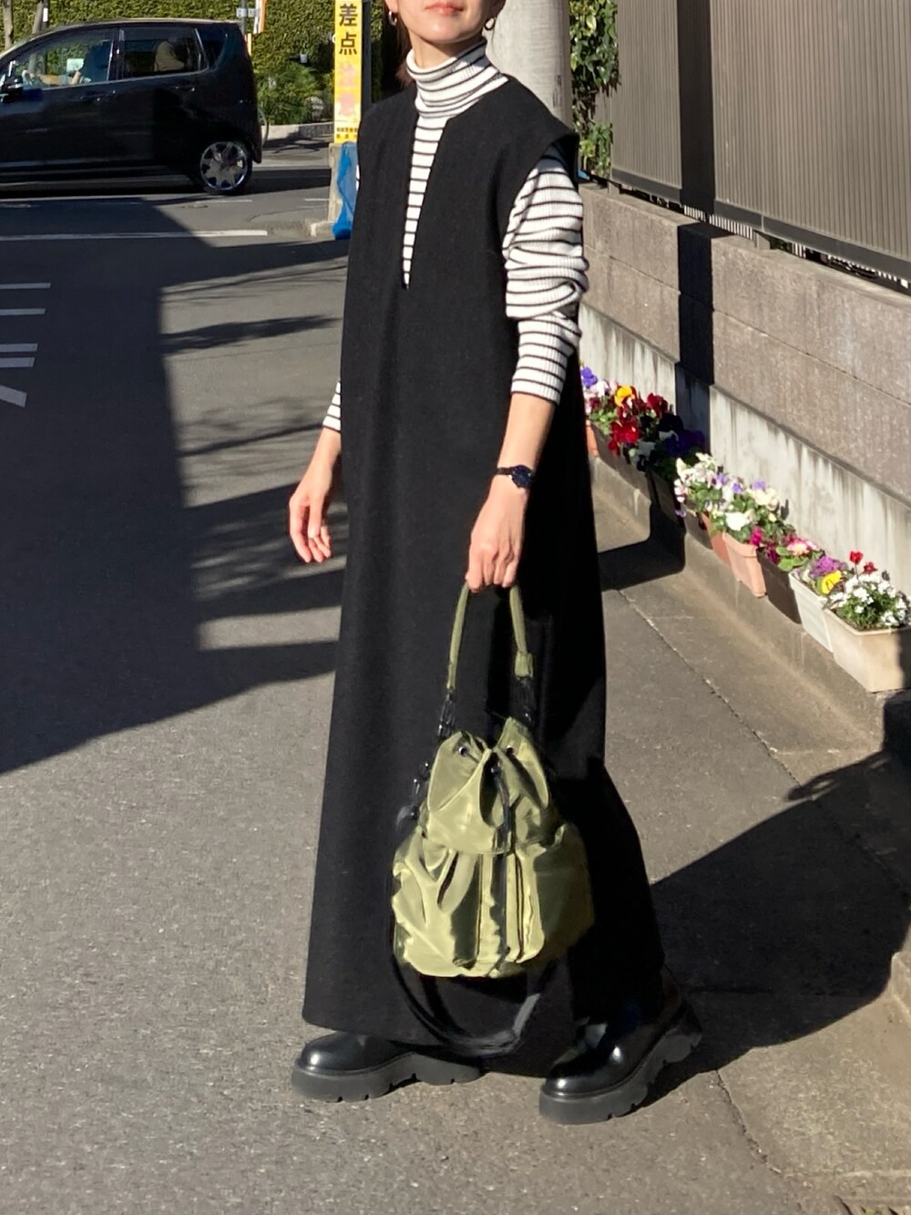 ホワイト系のニット/セーター、ブラック系のワンピース、グリーン系のショルダーバッグを着用したレディースの冬コーディネートの4枚目の写真