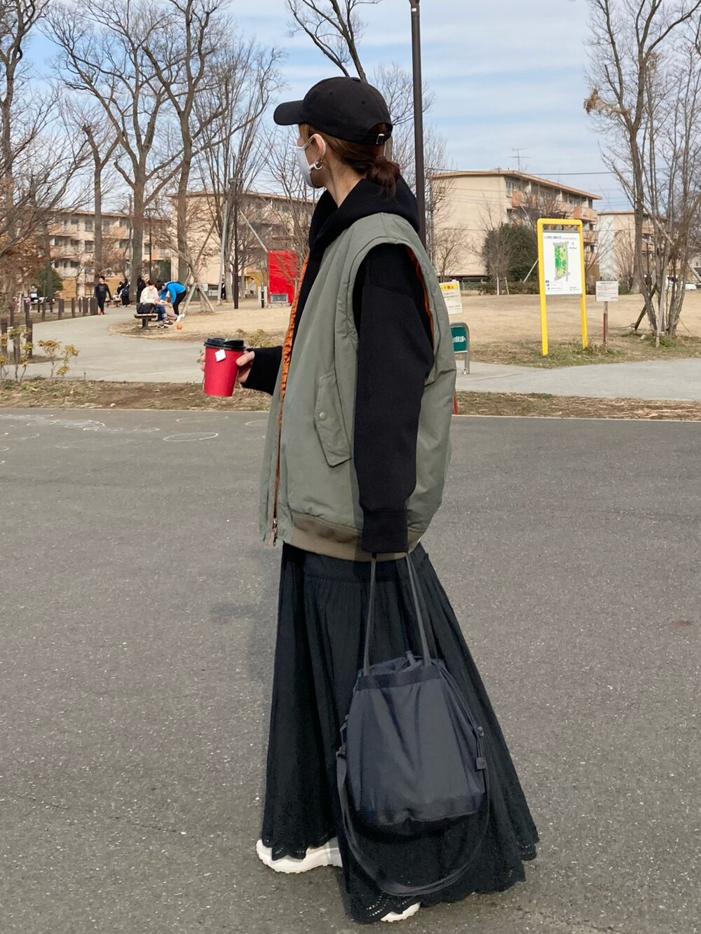 グリーン系のMA-1、ブラック系のパーカー、ブラック系のスカートを着用したレディースの春コーディネートの4枚目の写真