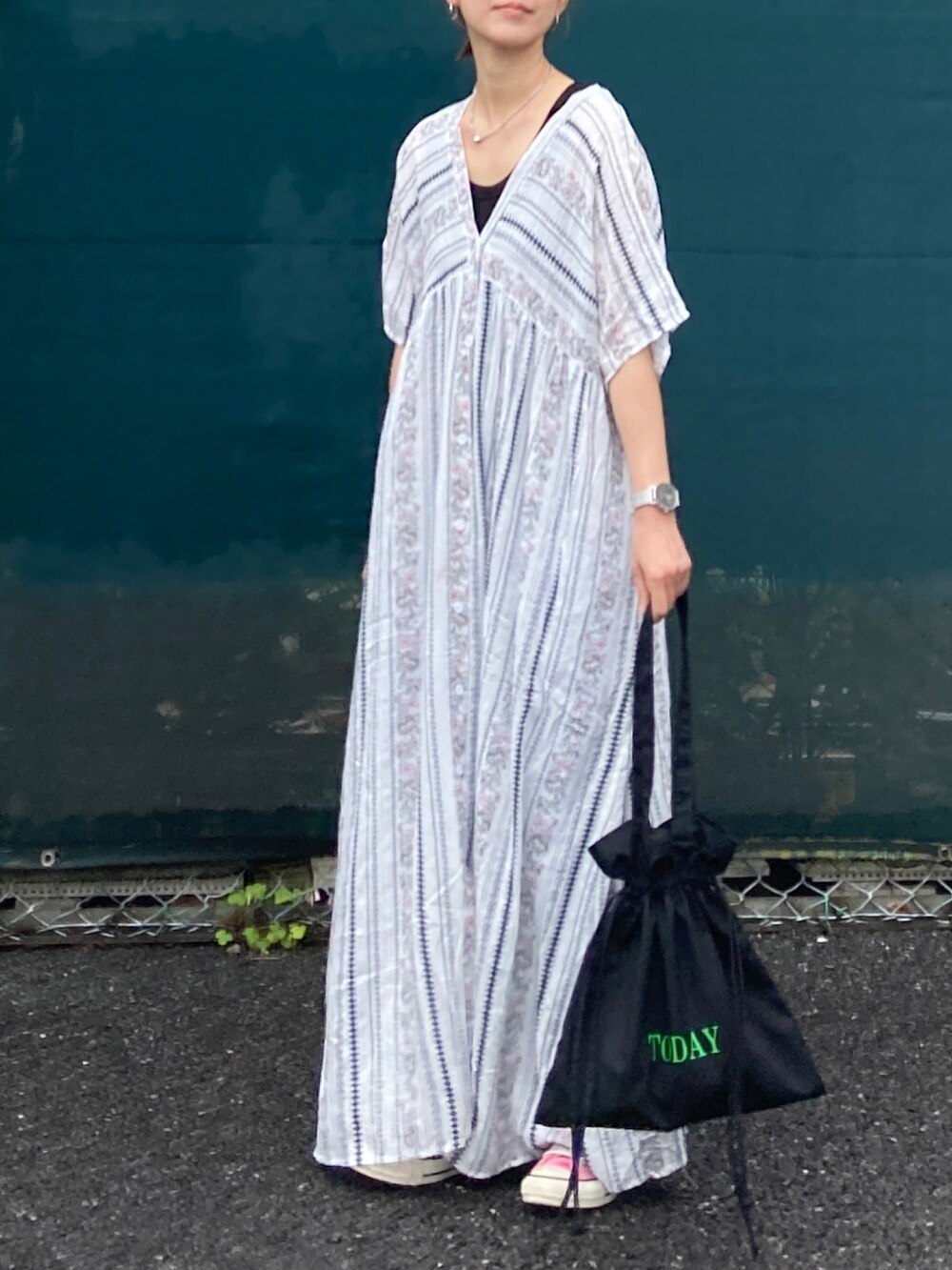 ホワイト系のワンピース、ブラック系のトートバッグ、ブルー系のデニムパンツを着用したレディースの春コーディネートの3枚目の写真