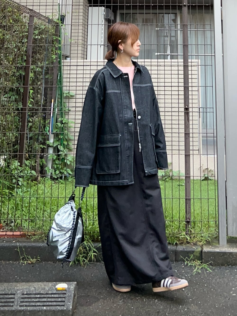 オレンジ系のTシャツ/カットソー、ブラック系のデニムジャケット、シルバー系のトートバッグを着用したレディースの秋コーディネートの2枚目の写真