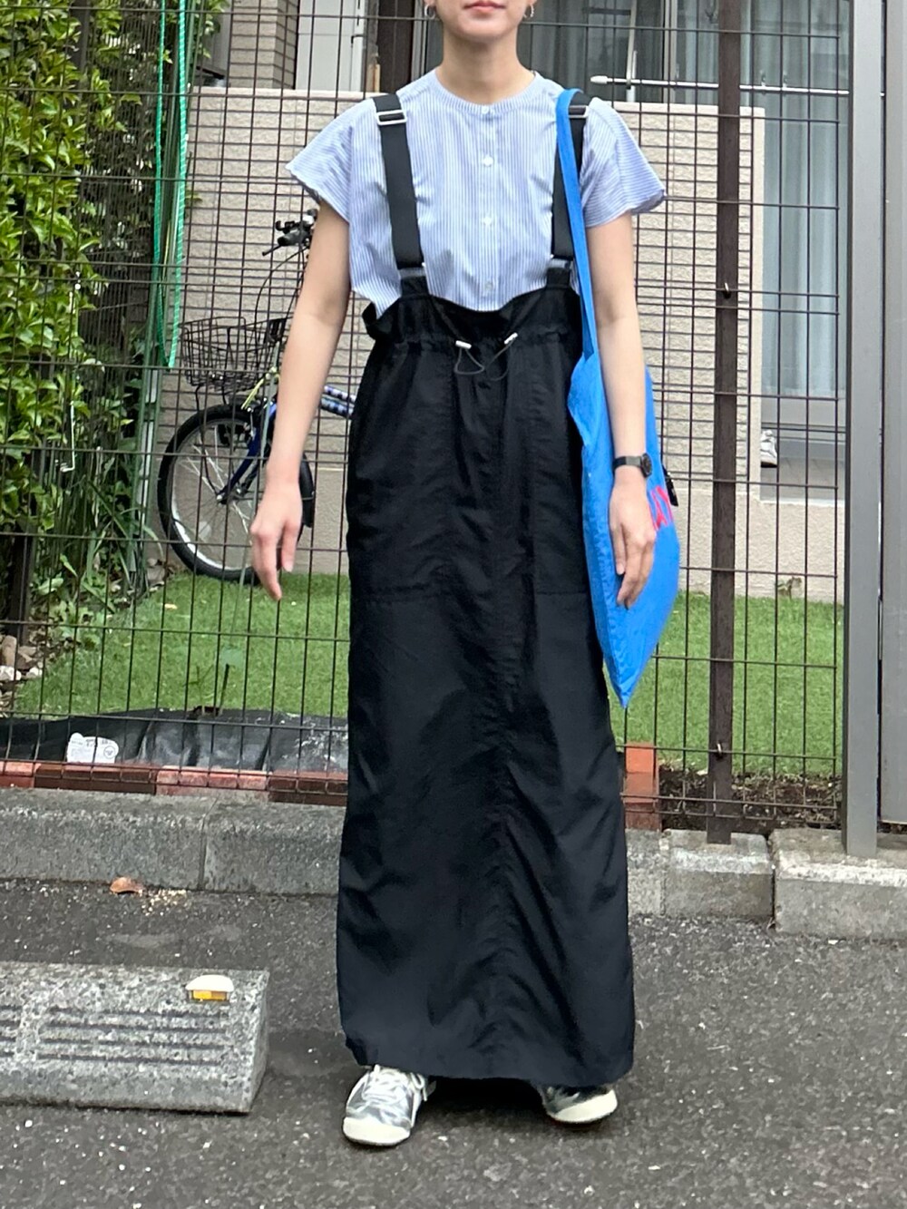 ブルー系のシャツ/ブラウス、ブラック系のジャンパースカート、シルバー系のスニーカーを着用したレディースの春コーディネートの4枚目の写真