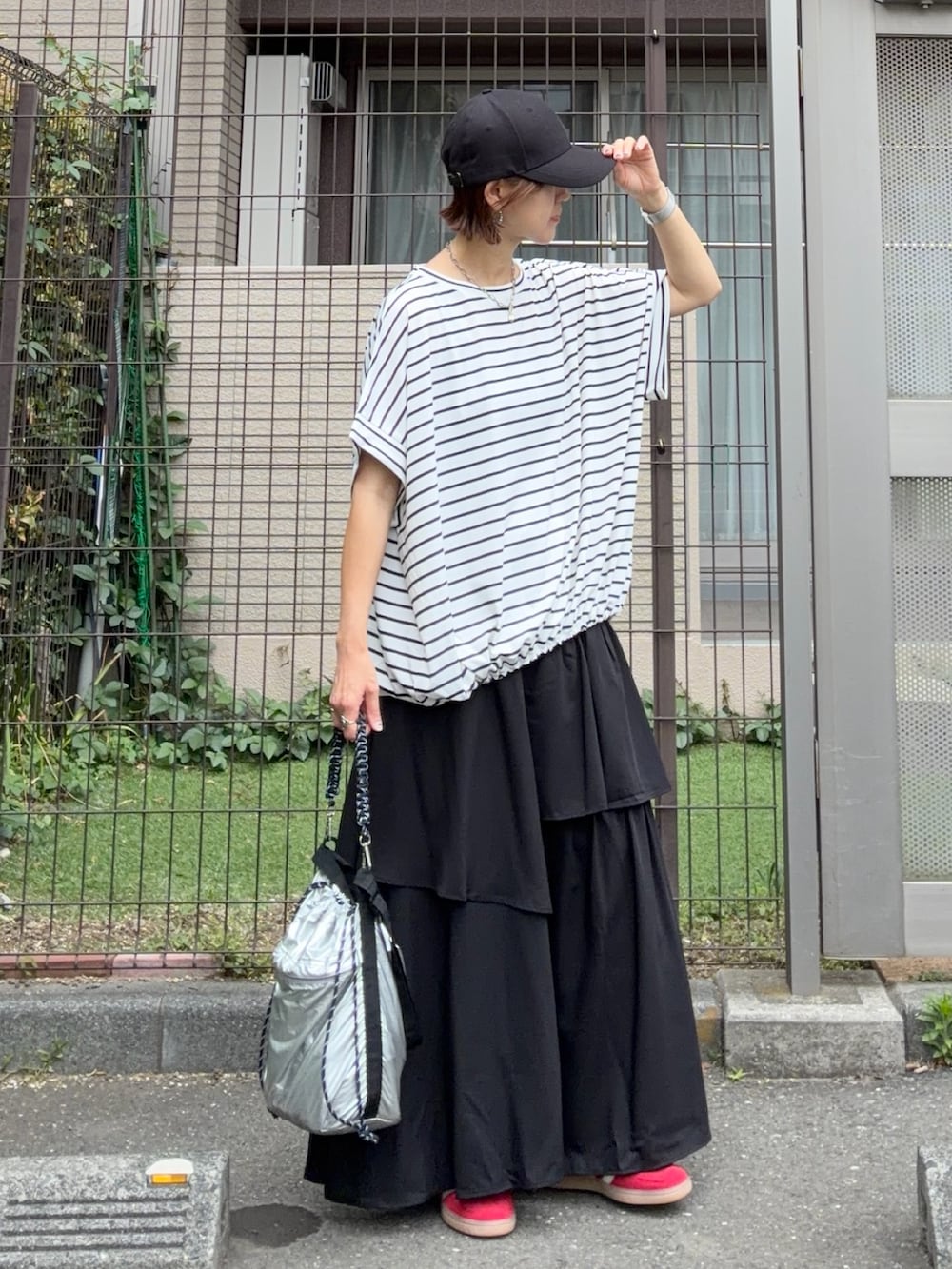 ブラック系のスカート、シルバー系のショルダーバッグ、ホワイト系のTシャツ/カットソーを着用したレディースの春コーディネートの2枚目の写真