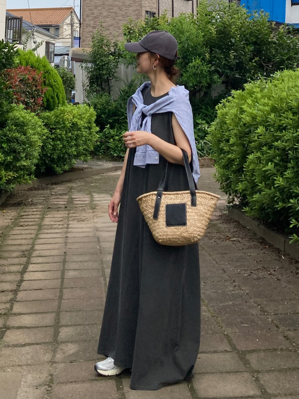グレー系のワンピース、ブラック系のかごバッグ、グレー系のキャップを着用したレディースの夏コーディネートの2枚目の写真