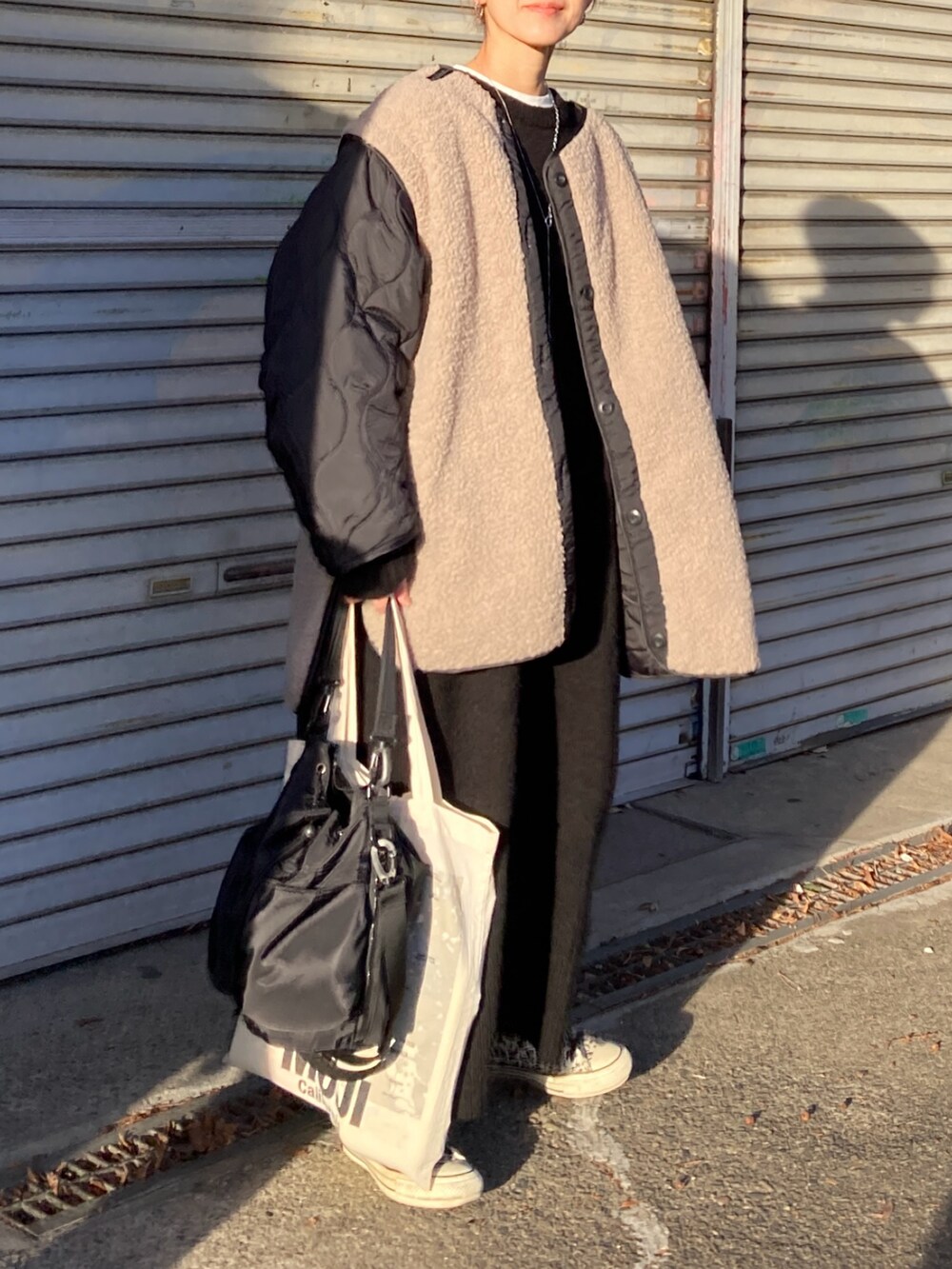 ブラック系のブルゾン、ブラック系のショルダーバッグ、ブラック系のワンピースを着用したレディースの冬コーディネートの2枚目の写真