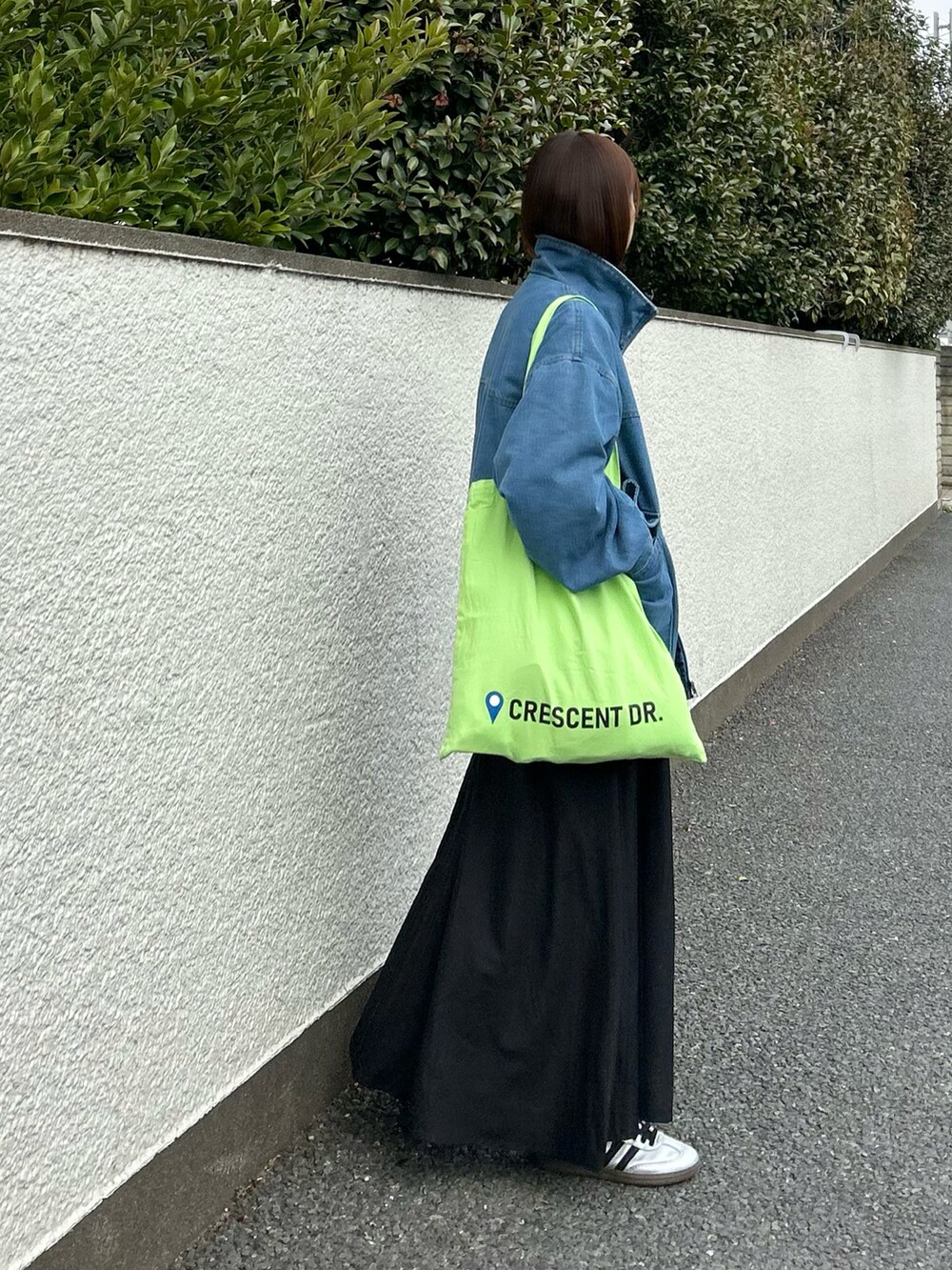 ブルー系のデニムジャケット、ブラック系のワンピース、グリーン系のトートバッグを着用したレディースの春コーディネートの3枚目の写真