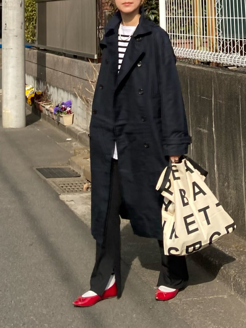 ブルー系のトレンチコート、ブラック系のTシャツ/カットソー、ホワイト系のトートバッグを着用したレディースの冬コーディネートの2枚目の写真