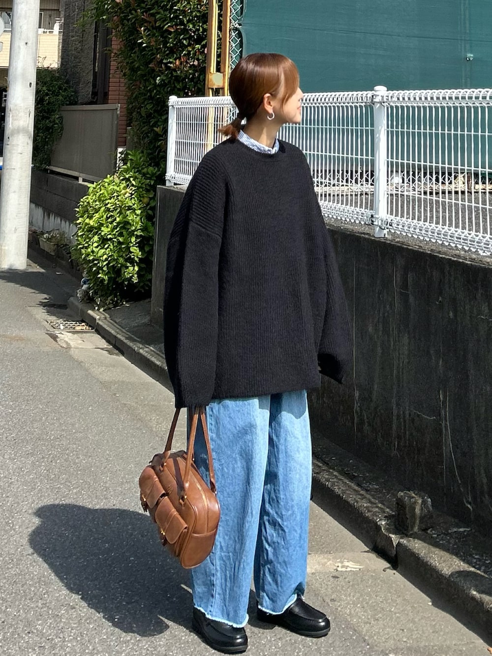 ブラック系のニット/セーター、ブルー系のデニムパンツ、ブラウン系のハンドバッグを着用したレディースの秋コーディネートの2枚目の写真