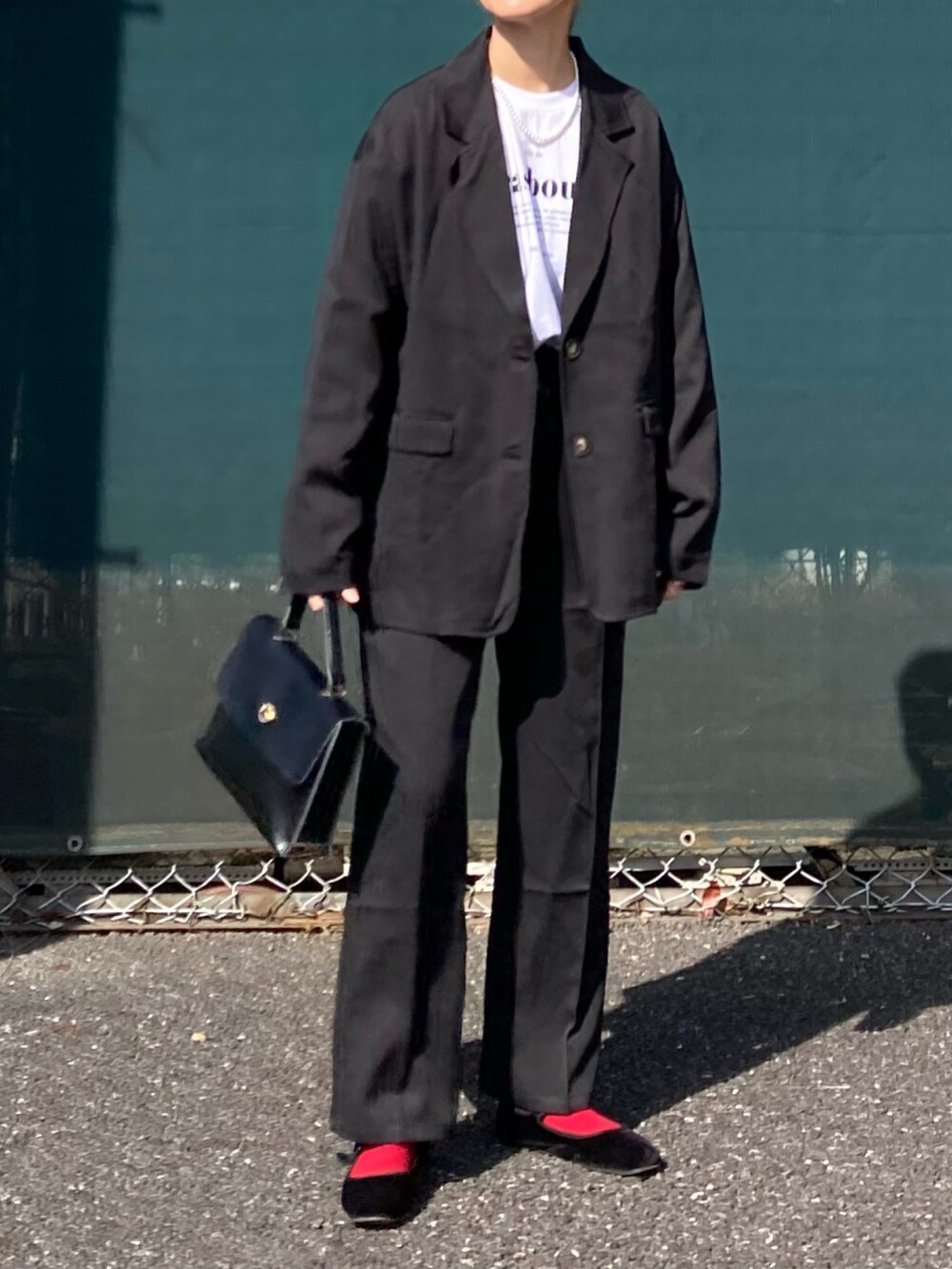 ブラック系のセットアップ、ホワイト系のTシャツ/カットソー、ブラック系のショルダーバッグを着用したレディースの冬コーディネートの4枚目の写真