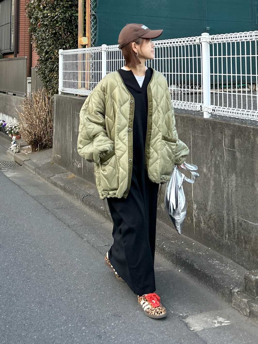 グリーン系のブルゾン、ブラック系のワンピース、シルバー系のクラッチバッグを着用したレディースの冬コーディネートの3枚目の写真