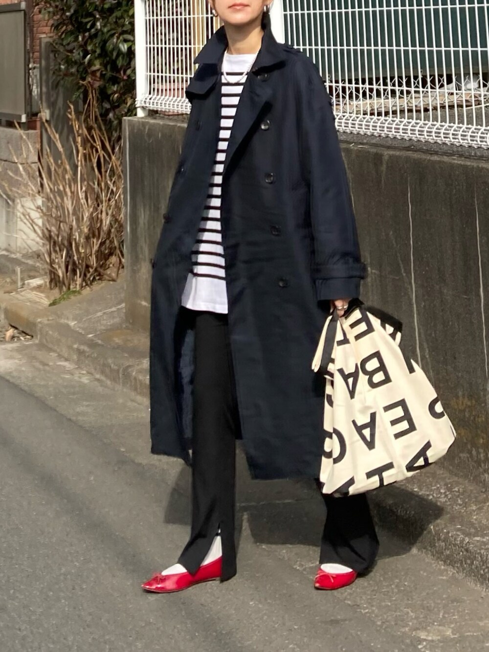 ブルー系のトレンチコート、ブラック系のTシャツ/カットソー、ホワイト系のトートバッグを着用したレディースの冬コーディネートの3枚目の写真