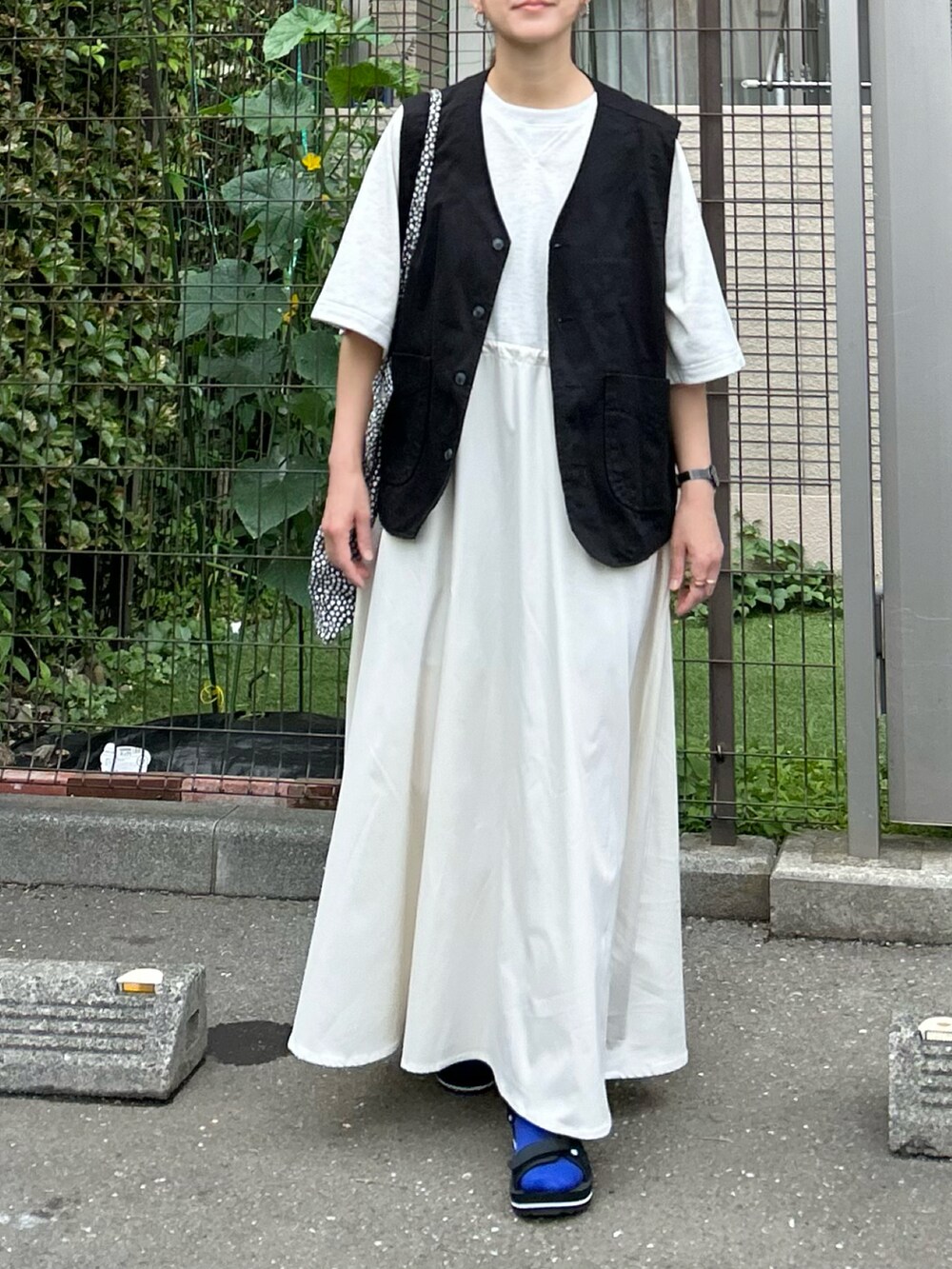 ベージュ系のワンピース、ブラック系のベスト、ブラック系のサンダルを着用したレディースの夏コーディネートの5枚目の写真