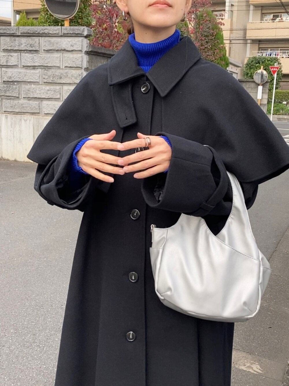 ブラック系のステンカラーコート、ブルー系のニット/セーター、ブラック系のその他パンツを着用したレディースの秋コーディネートの4枚目の写真