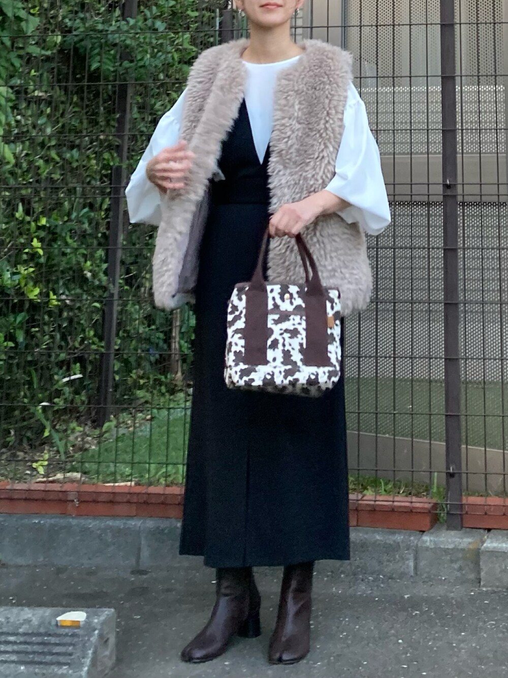 ベージュ系のベスト、ホワイト系のシャツ/ブラウス、ブラック系のジャンパースカートを着用したレディースの秋コーディネートの4枚目の写真