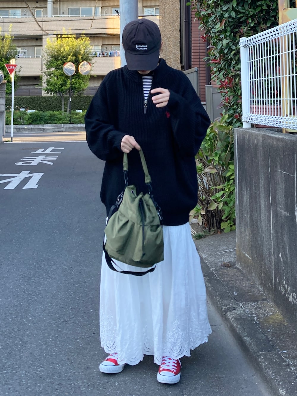 ブラック系のニット/セーター、ホワイト系のスカート、グリーン系のショルダーバッグを着用したレディースの秋コーディネートの2枚目の写真