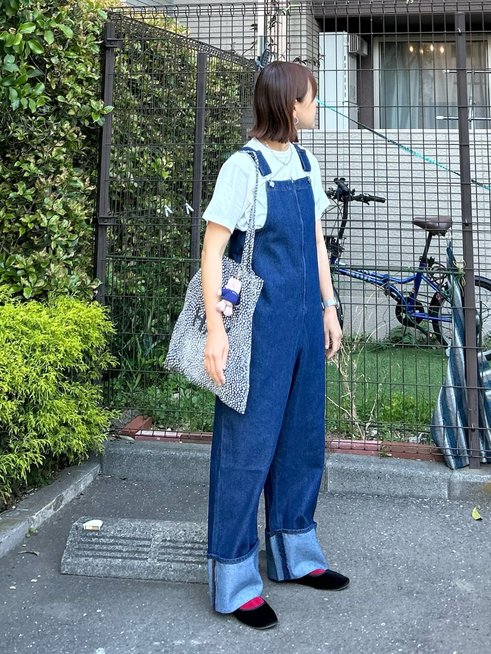 ブルー系のサロペット/オーバーオール、ブラック系のTシャツ/カットソー、ベージュ系のチャームを着用したレディースの春コーディネートの3枚目の写真