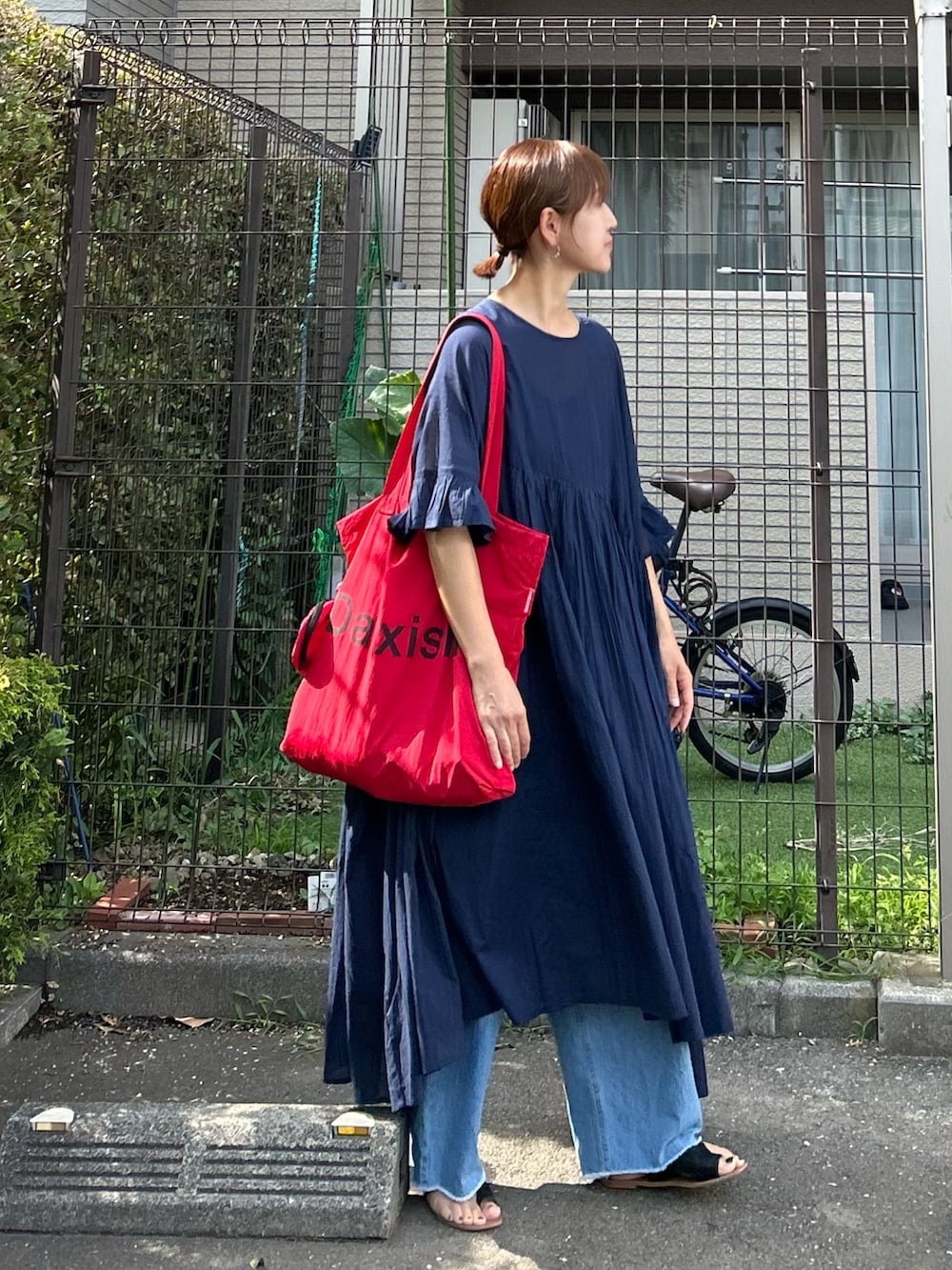 ブルー系のデニムパンツ、ブルー系のワンピース、レッド系のトートバッグを着用したレディースの夏コーディネートの3枚目の写真