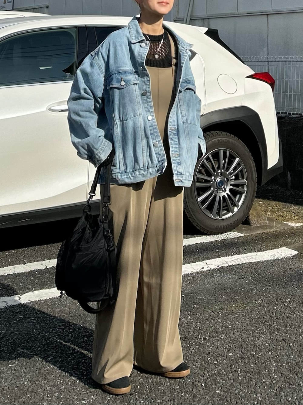 ブラック系のニット/セーター、ブルー系のデニムジャケット、ベージュ系のサロペット/オーバーオールを着用したレディースの春コーディネートの3枚目の写真