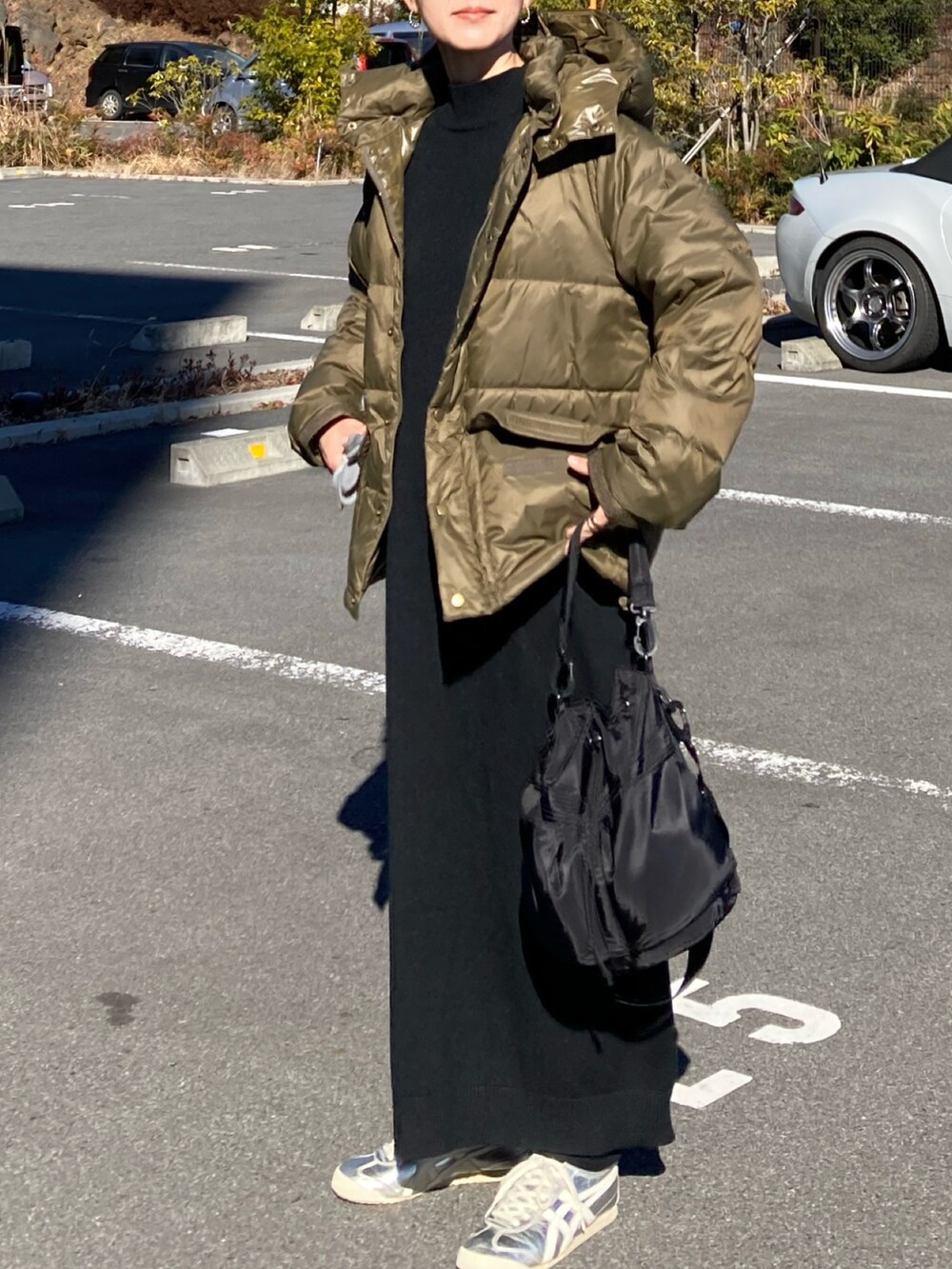 グリーン系のダウンジャケット/コート、ブラック系のワンピース、ブラック系のショルダーバッグを着用したレディースの冬コーディネートの2枚目の写真