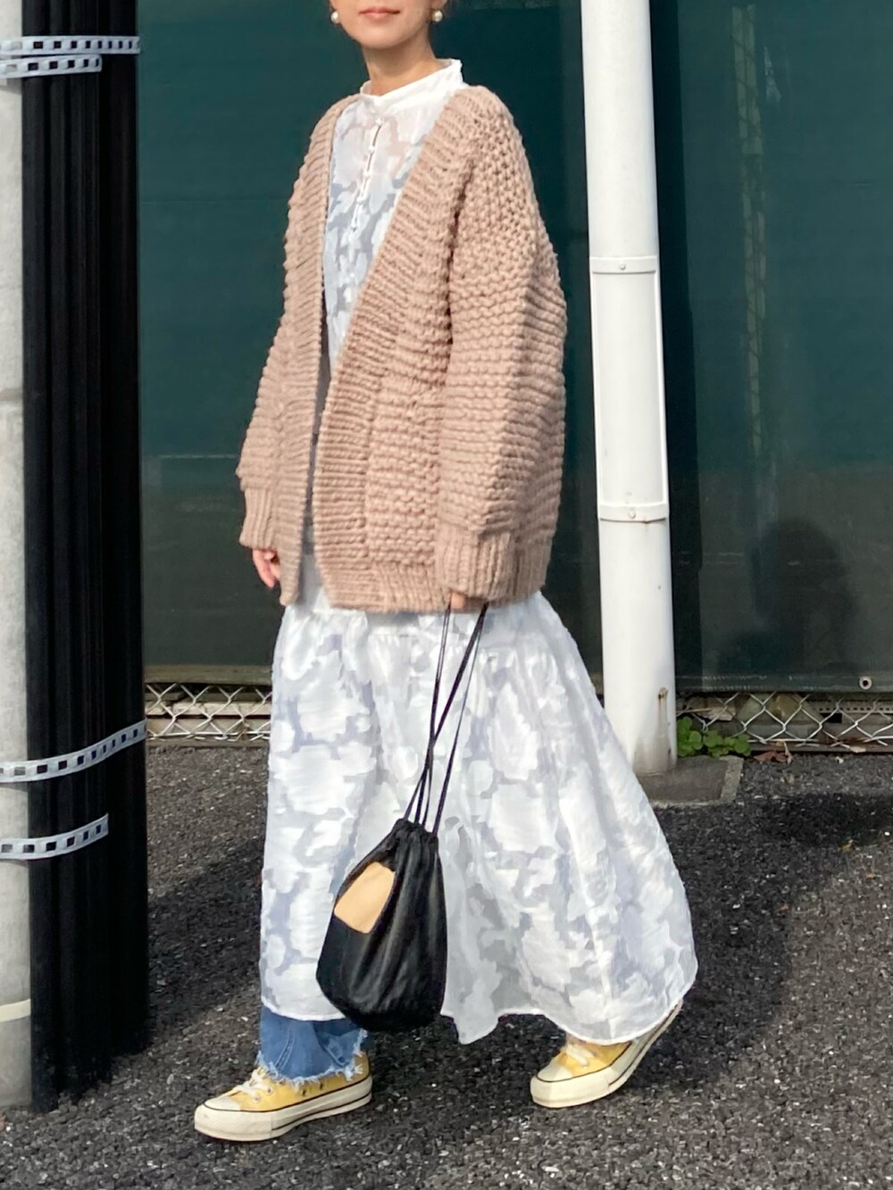 ホワイト系のワンピース、ベージュ系のカーディガン/ボレロ、ブルー系のデニムパンツを着用したレディースの秋コーディネートの3枚目の写真