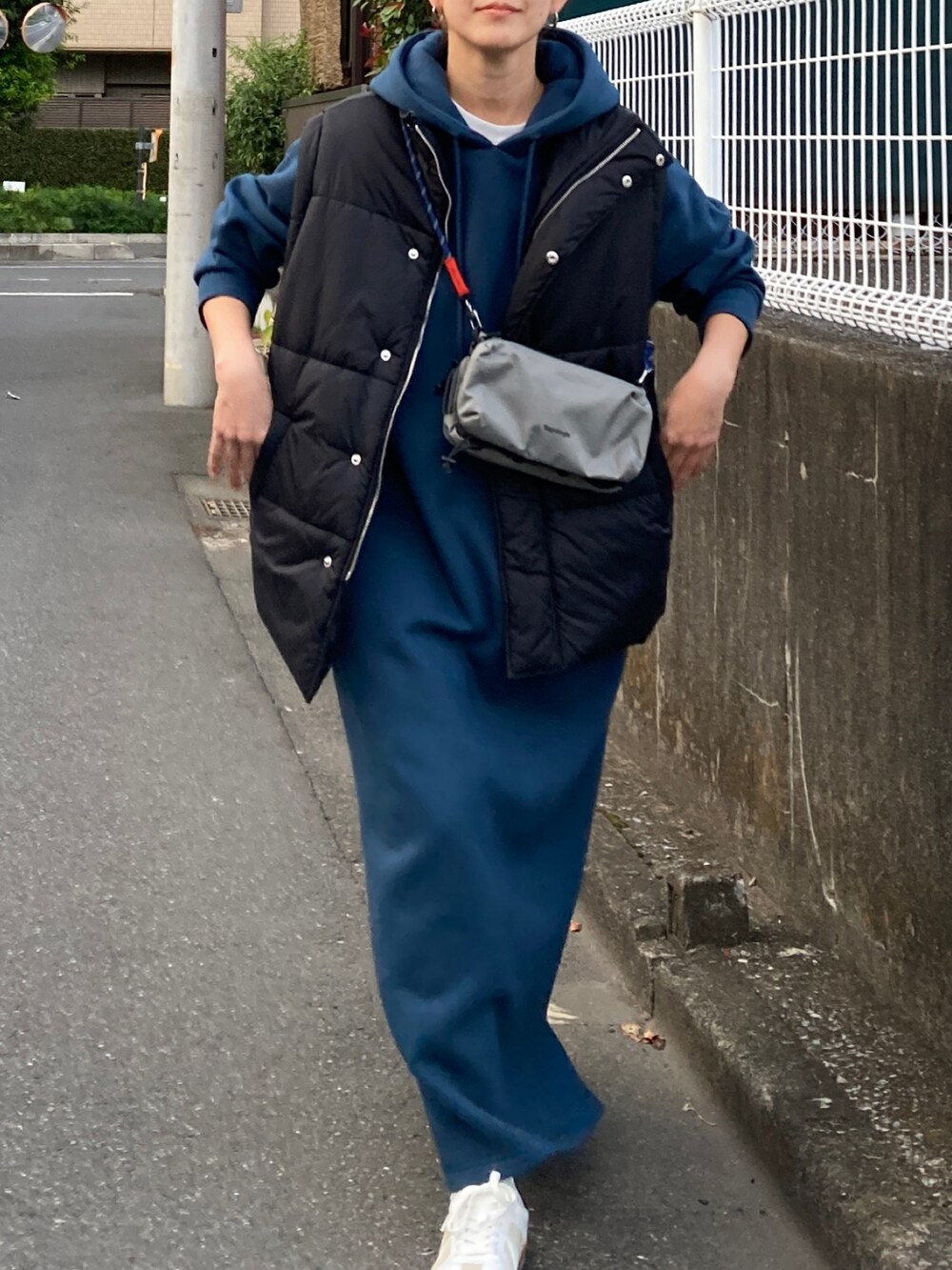 ブラック系のダウンベスト、ブルー系のワンピース、グレー系のショルダーバッグを着用したレディースの秋コーディネートの5枚目の写真