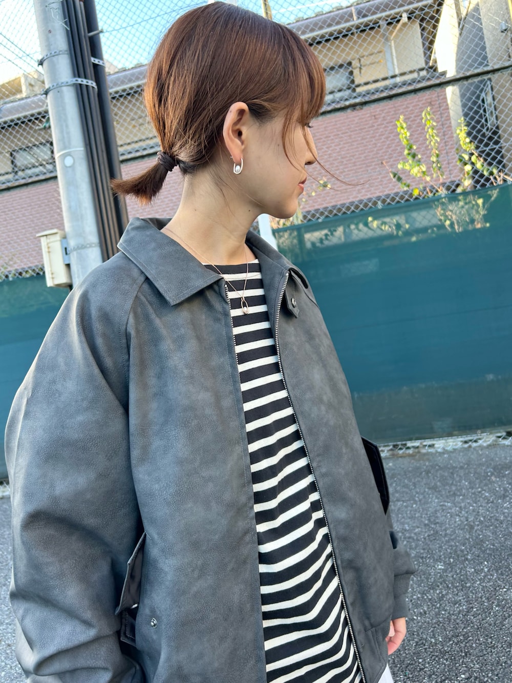 ブラック系のブルゾン、ブラック系のトートバッグ、ホワイト系のスカートを着用したレディースの秋コーディネートの2枚目の写真