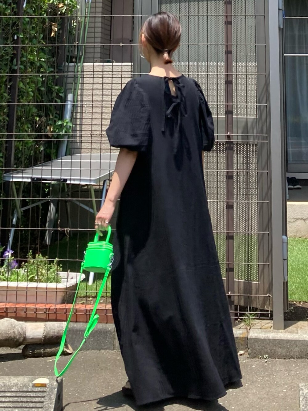 ブラック系のワンピース、グリーン系のショルダーバッグ、シルバー系のピアス（両耳用）を着用したレディースの夏コーディネートの3枚目の写真