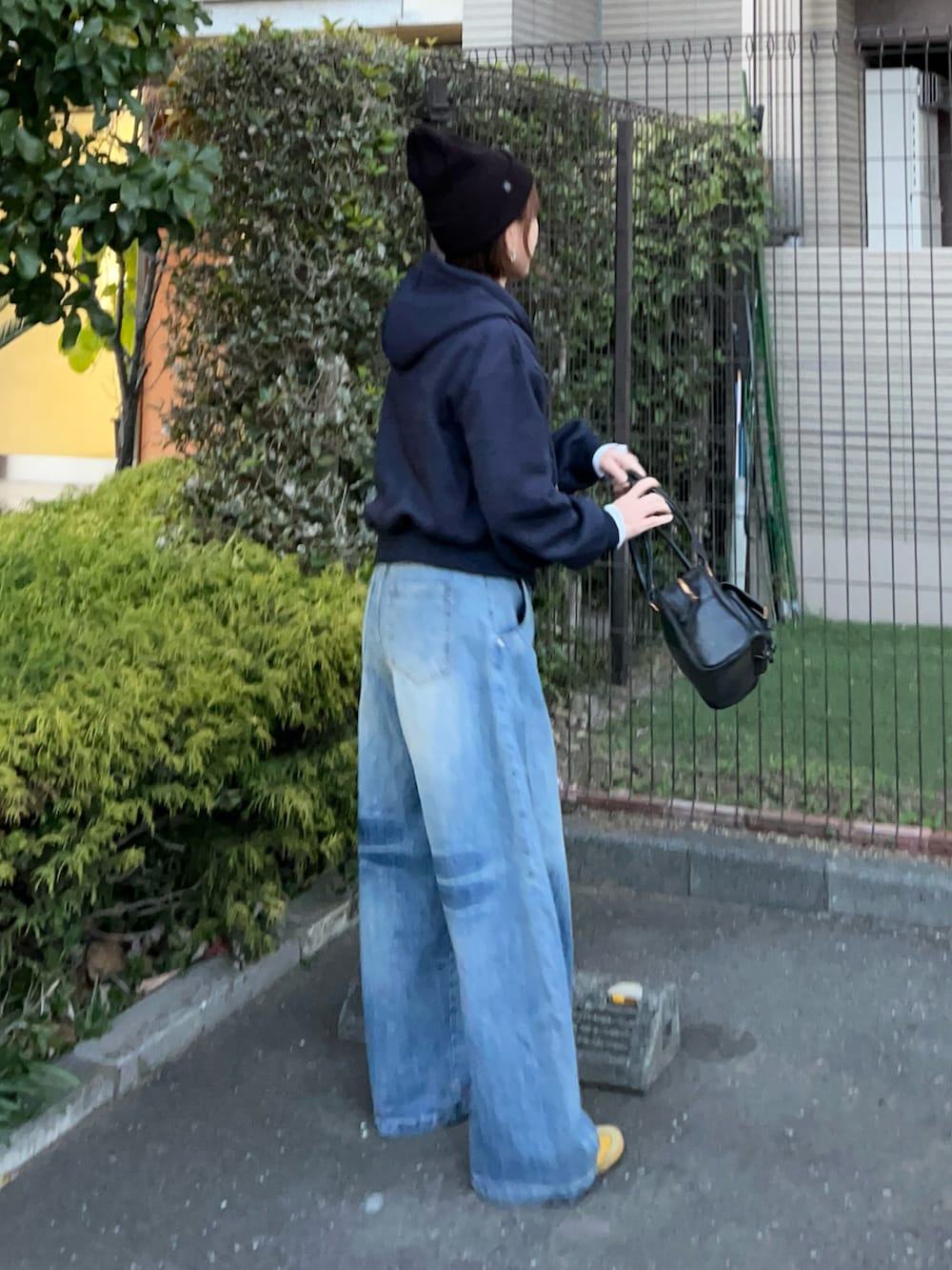 ブルー系のパーカー、ブラック系のハンドバッグ、イエロー系のスニーカーを着用したレディースの冬コーディネートの3枚目の写真