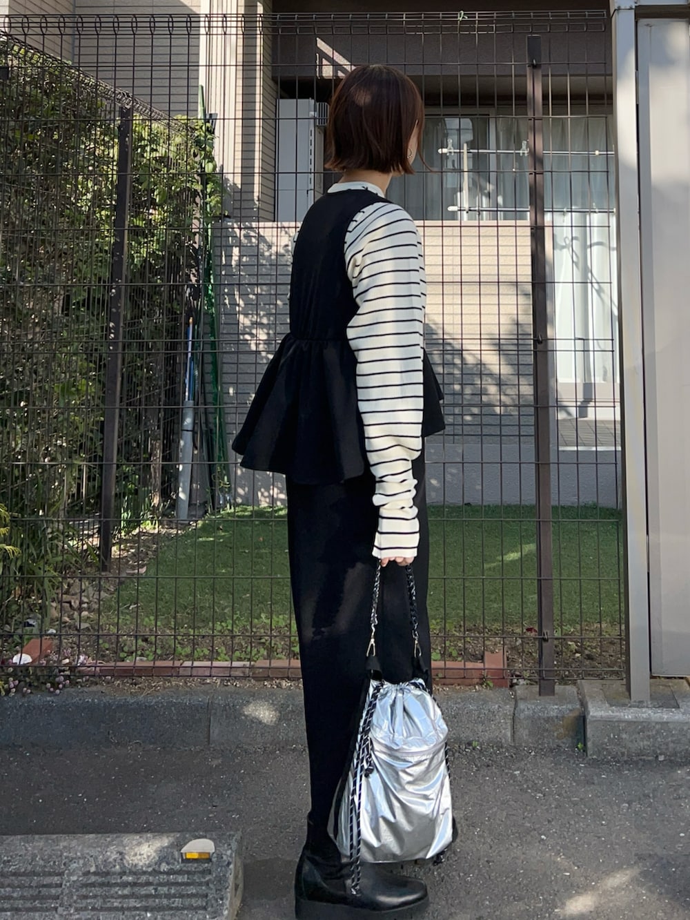 ブラック系のジャンパースカート、ホワイト系のニット/セーター、シルバー系のトートバッグを着用したレディースの冬コーディネートの3枚目の写真