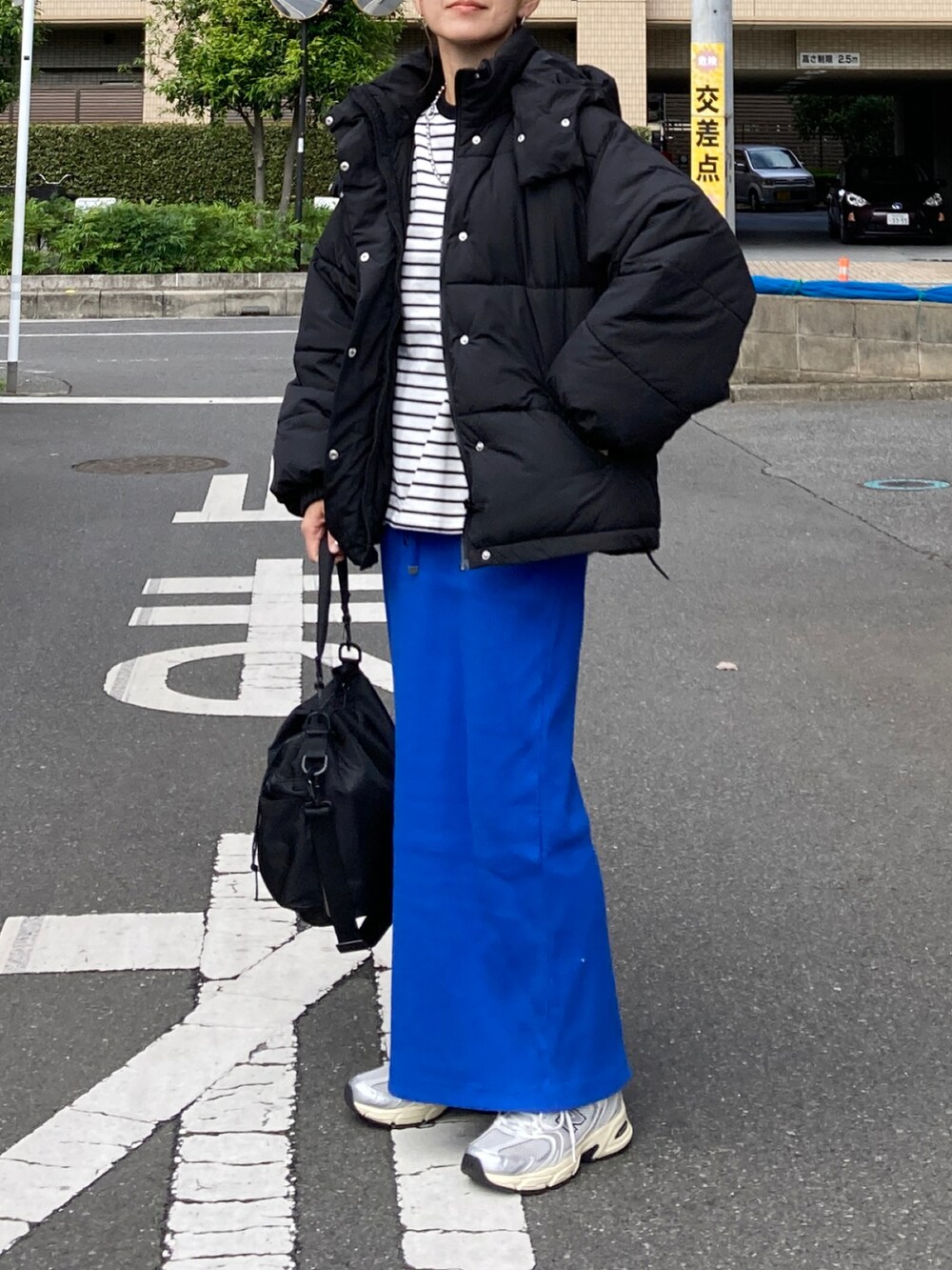 ブラック系のダウンジャケット/コート、ブラック系のTシャツ/カットソー、ブルー系のスカートを着用したレディースの秋コーディネートの2枚目の写真