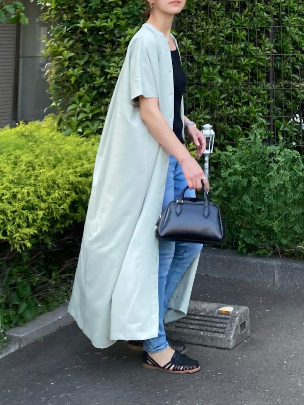 グリーン系のワンピース、ブルー系のデニムパンツ、ブラック系のボストンバッグを着用したレディースの春コーディネートの2枚目の写真