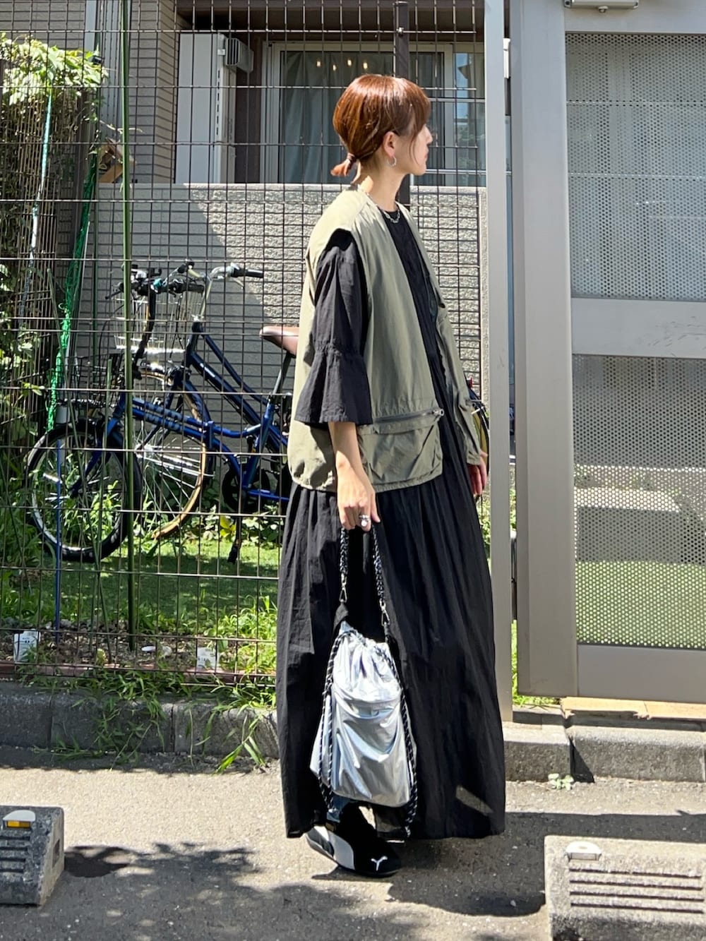 ブラック系のワンピース、シルバー系のトートバッグ、グリーン系のベストを着用したレディースの秋コーディネートの3枚目の写真