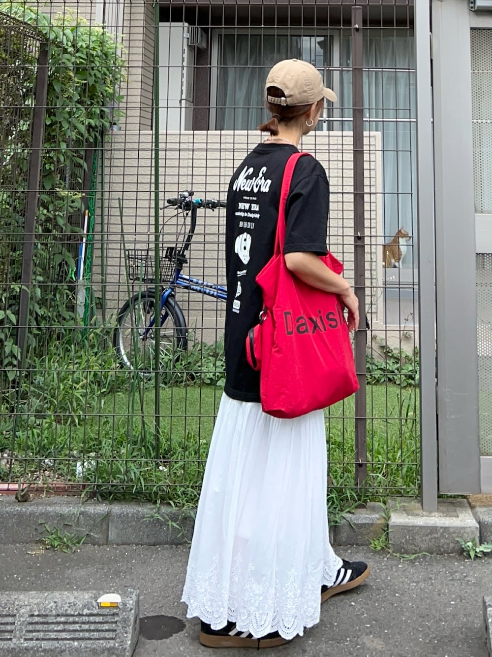 ブラック系のTシャツ/カットソー、レッド系のトートバッグ、ホワイト系のスカートを着用したレディースの夏コーディネートの3枚目の写真