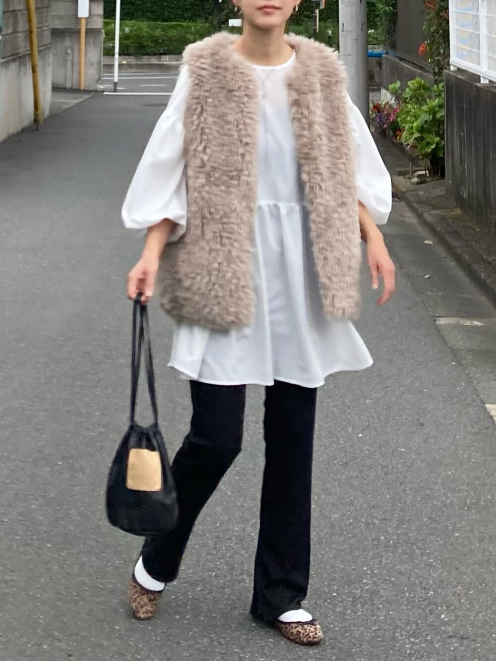 ベージュ系のベスト、ホワイト系のシャツ/ブラウス、ブラック系のハンドバッグを着用したレディースの秋コーディネートの4枚目の写真