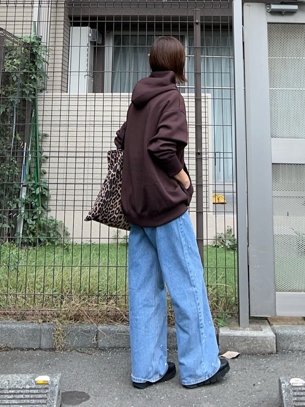ブラウン系のパーカー、ブルー系のデニムパンツ、ブラウン系のトートバッグを着用したレディースの秋コーディネートの2枚目の写真