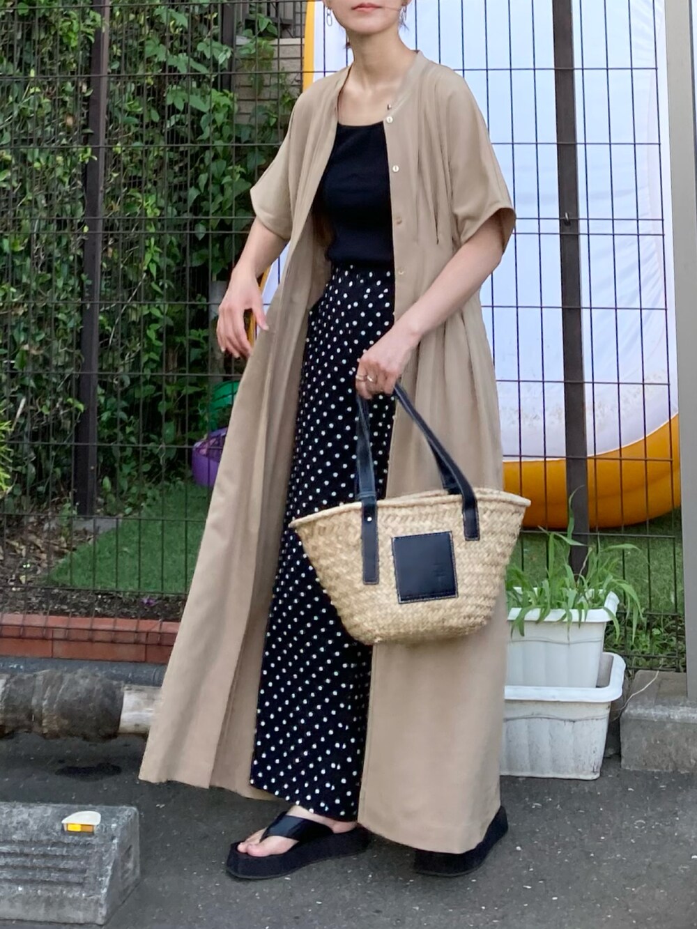 ベージュ系のワンピース、ブラック系のその他パンツ、ブラック系のかごバッグを着用したレディースの夏コーディネートの2枚目の写真