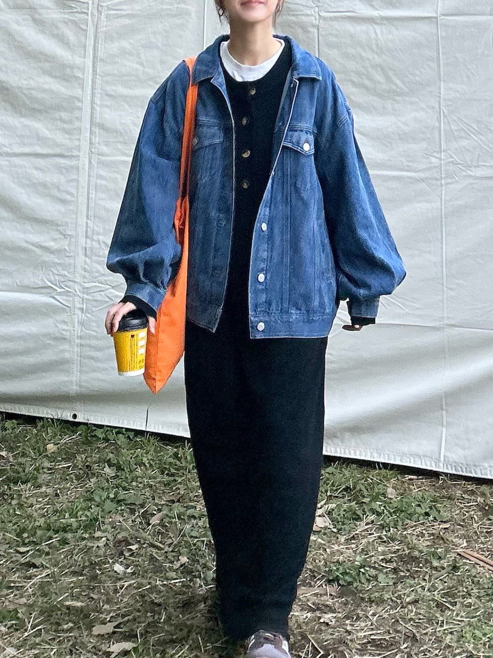 ブラック系のワンピース、ブルー系のデニムジャケット、オレンジ系のトートバッグを着用したレディースの冬コーディネートの4枚目の写真