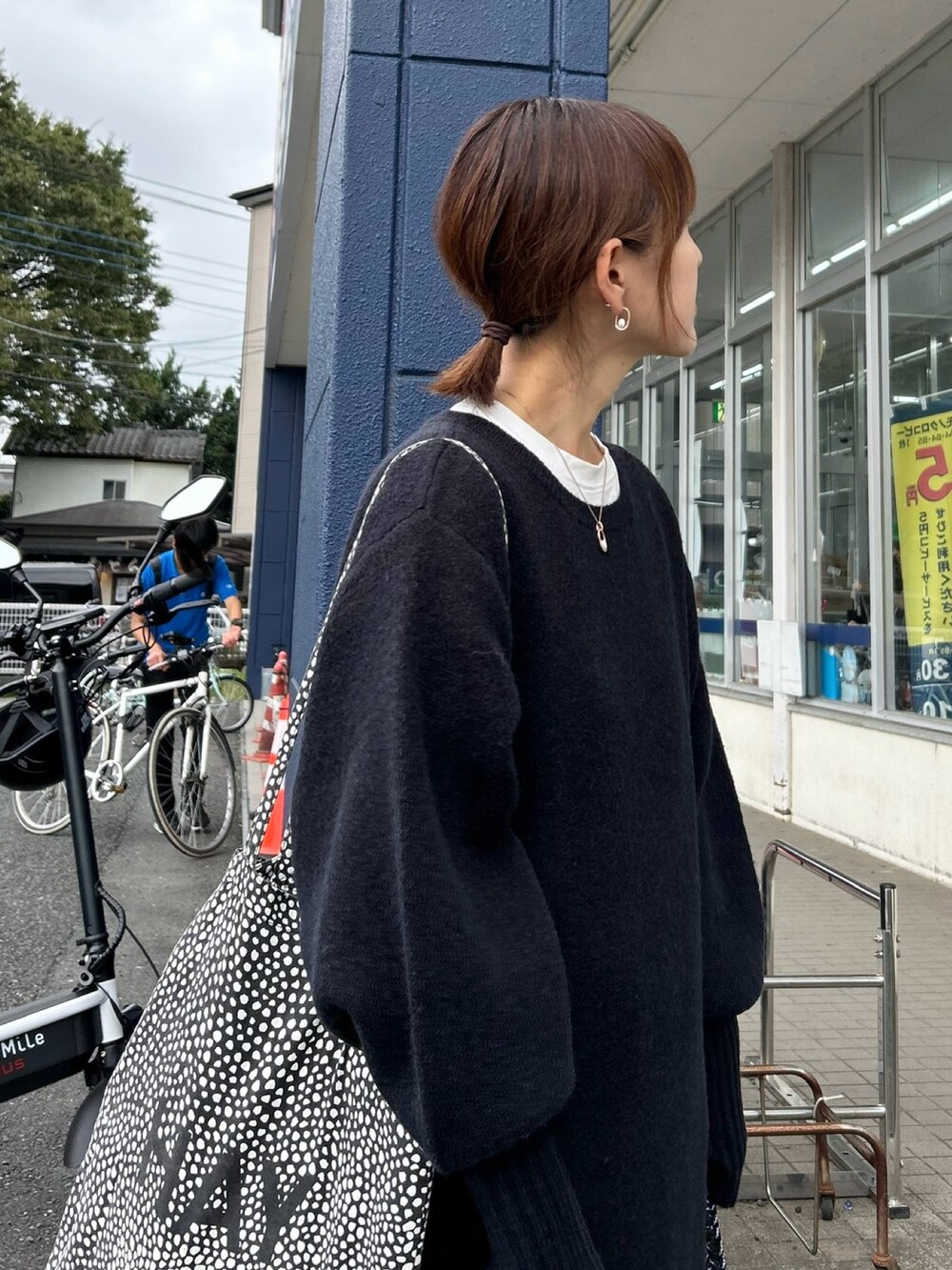 ブラック系のワンピース、グリーン系のショルダーバッグ、シルバー系のスニーカーを着用したレディースの秋コーディネートの2枚目の写真