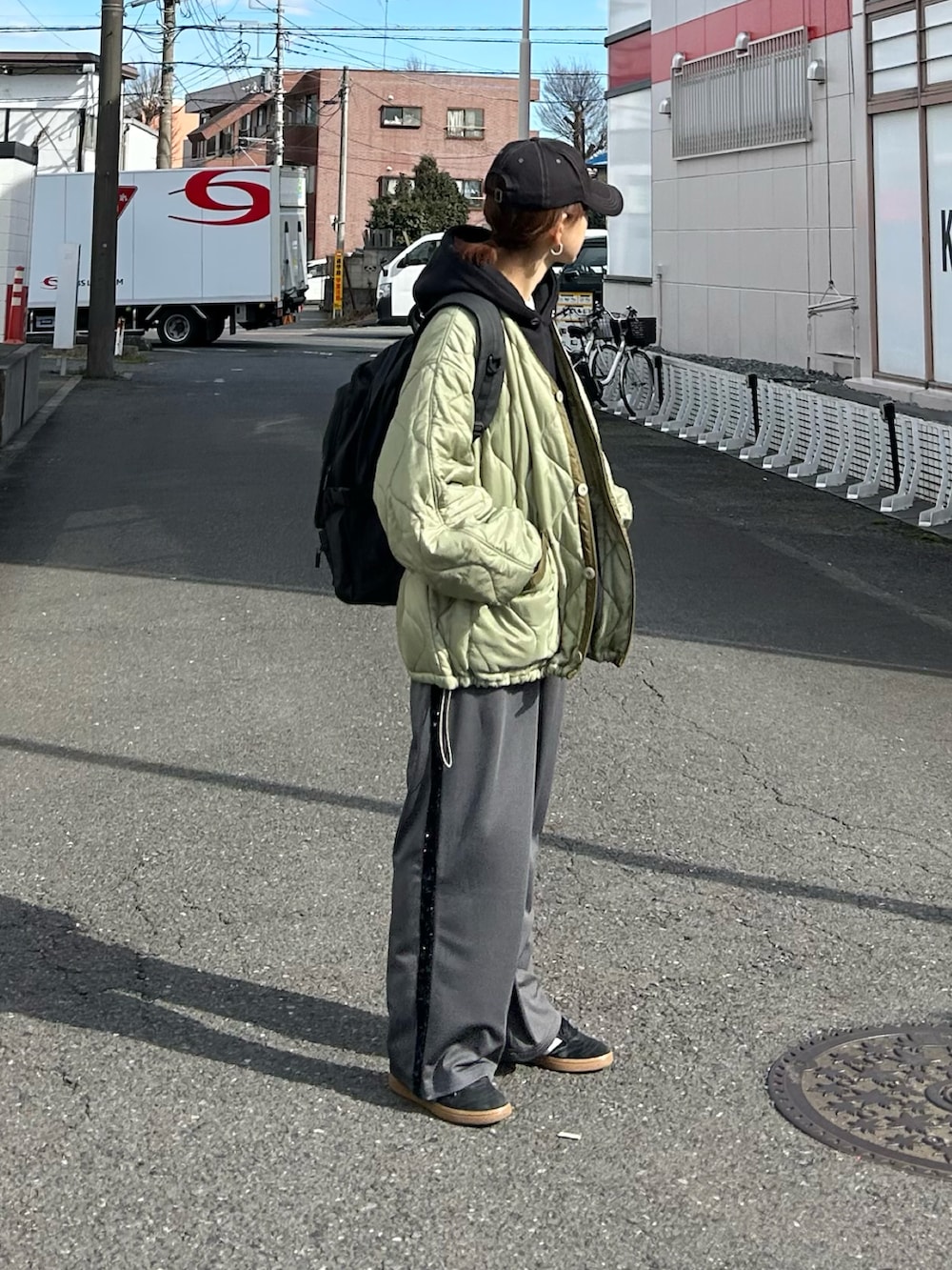 グリーン系のノーカラージャケット、ブラック系のパーカー、ブラック系のバックパック/リュックを着用したレディースの冬コーディネートの3枚目の写真