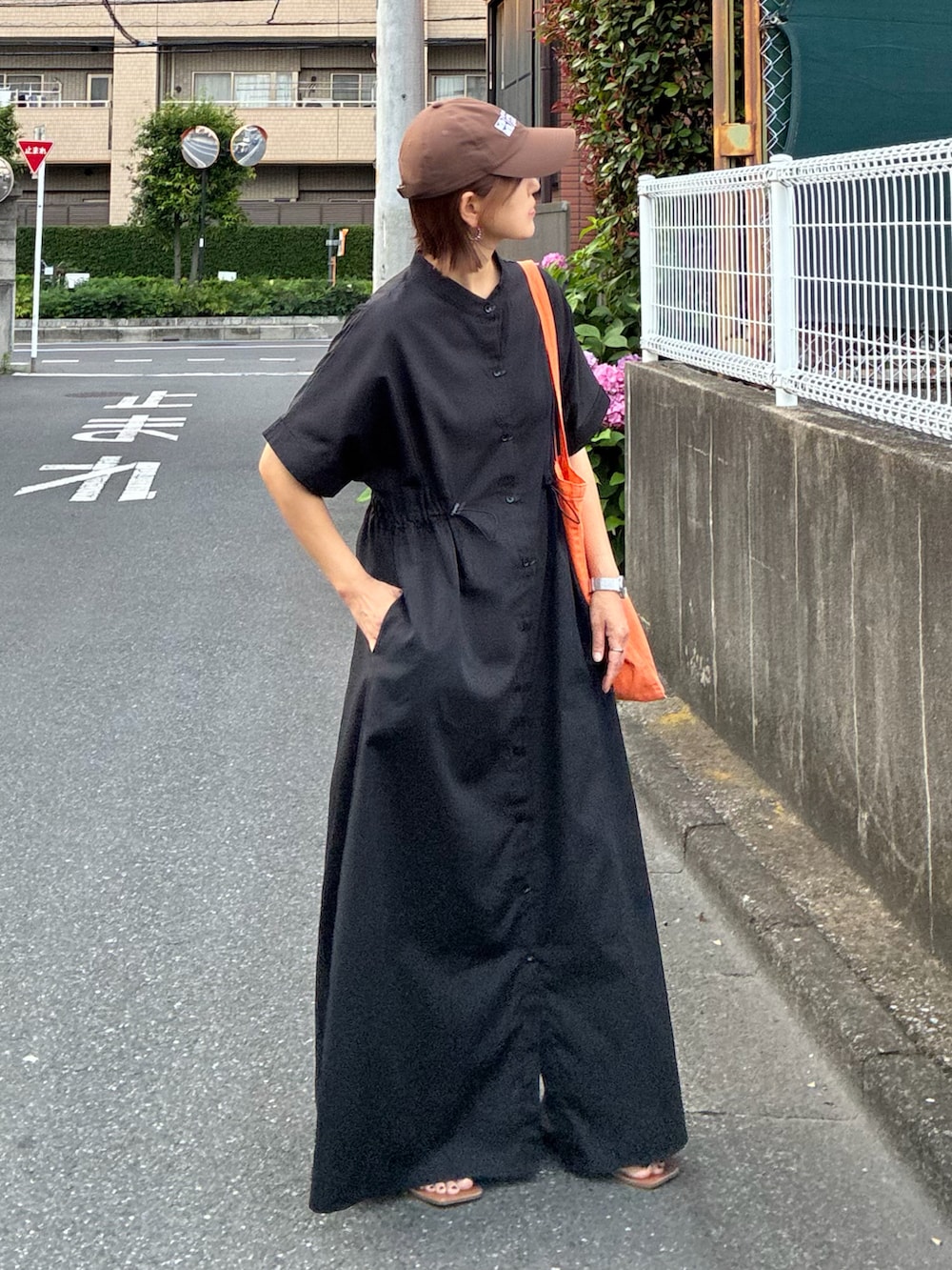 ブラック系のシャツワンピース、オレンジ系のトートバッグを着用したレディースの夏コーディネートの4枚目の写真