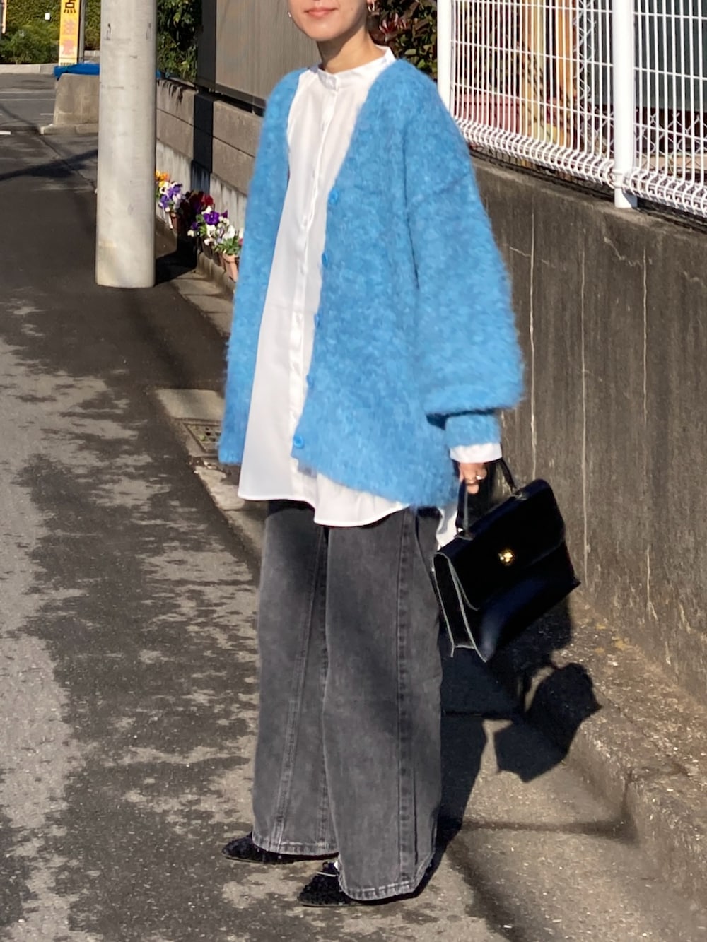 ブルー系のカーディガン/ボレロ、ホワイト系のシャツ/ブラウス、ブラック系のデニムパンツを着用したレディースの冬コーディネートの2枚目の写真