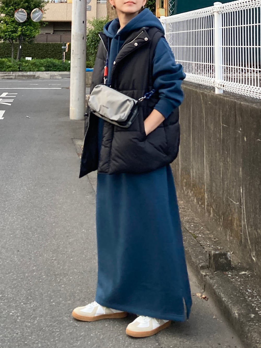 ブラック系のダウンベスト、ブルー系のワンピース、グレー系のショルダーバッグを着用したレディースの秋コーディネートの3枚目の写真