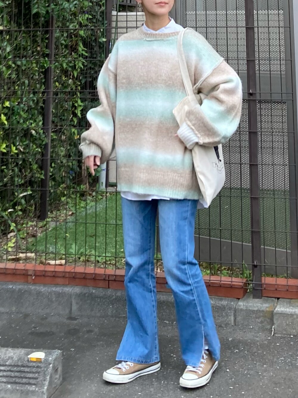 グリーン系のカーディガン/ボレロ、ホワイト系のシャツ/ブラウス、ブルー系のデニムパンツを着用したレディースの秋コーディネートの3枚目の写真