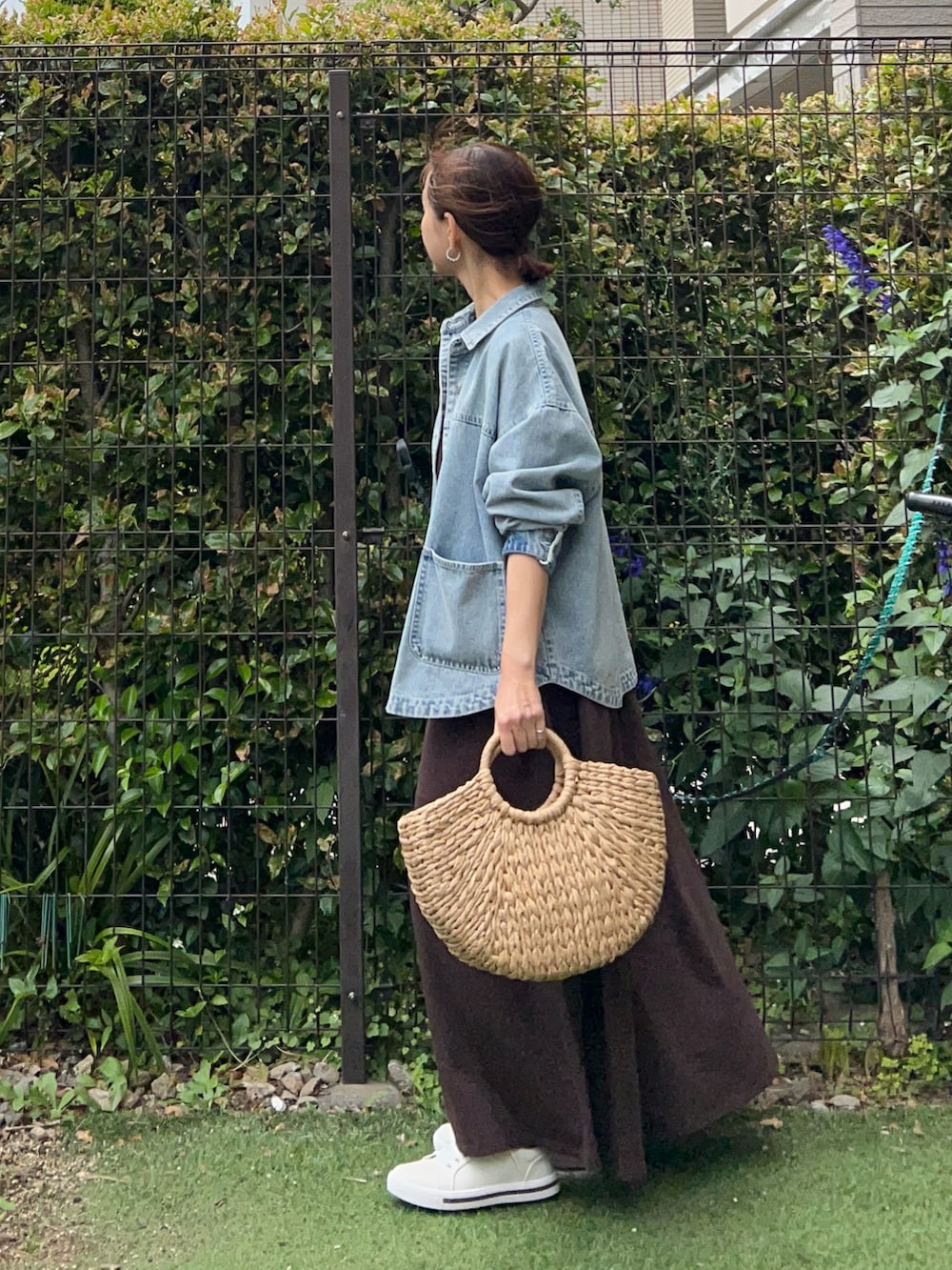 ブルー系のデニムジャケット、ブラウン系のワンピース、ベージュ系のかごバッグを着用したレディースの夏コーディネートの3枚目の写真