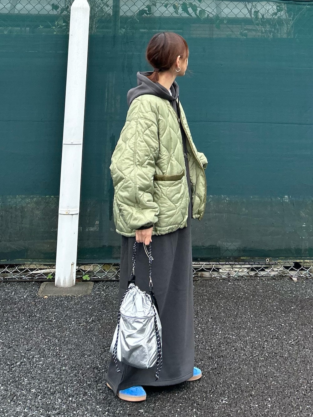 グレー系のワンピース、グリーン系のノーカラージャケット、シルバー系のトートバッグを着用したレディースの秋コーディネートの2枚目の写真