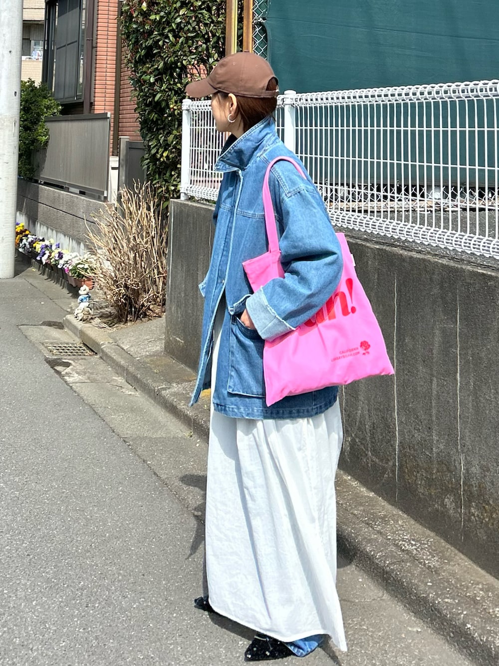 ブルー系のデニムジャケット、ホワイト系のワンピース、ピンク系のトートバッグを着用したレディースの春コーディネートの2枚目の写真