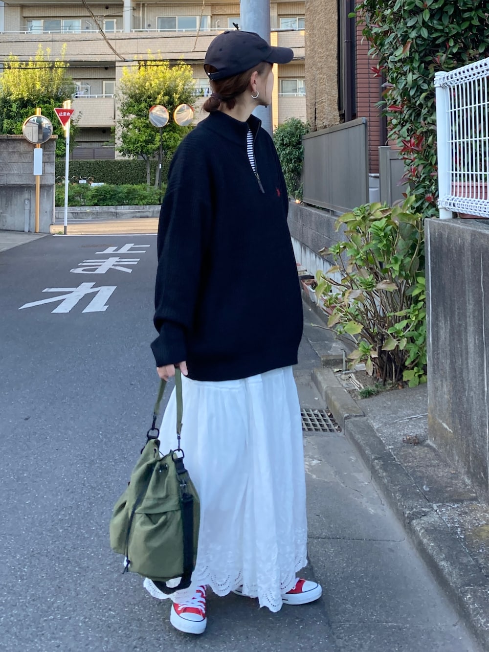 ブラック系のニット/セーター、ホワイト系のスカート、グリーン系のショルダーバッグを着用したレディースの秋コーディネートの3枚目の写真