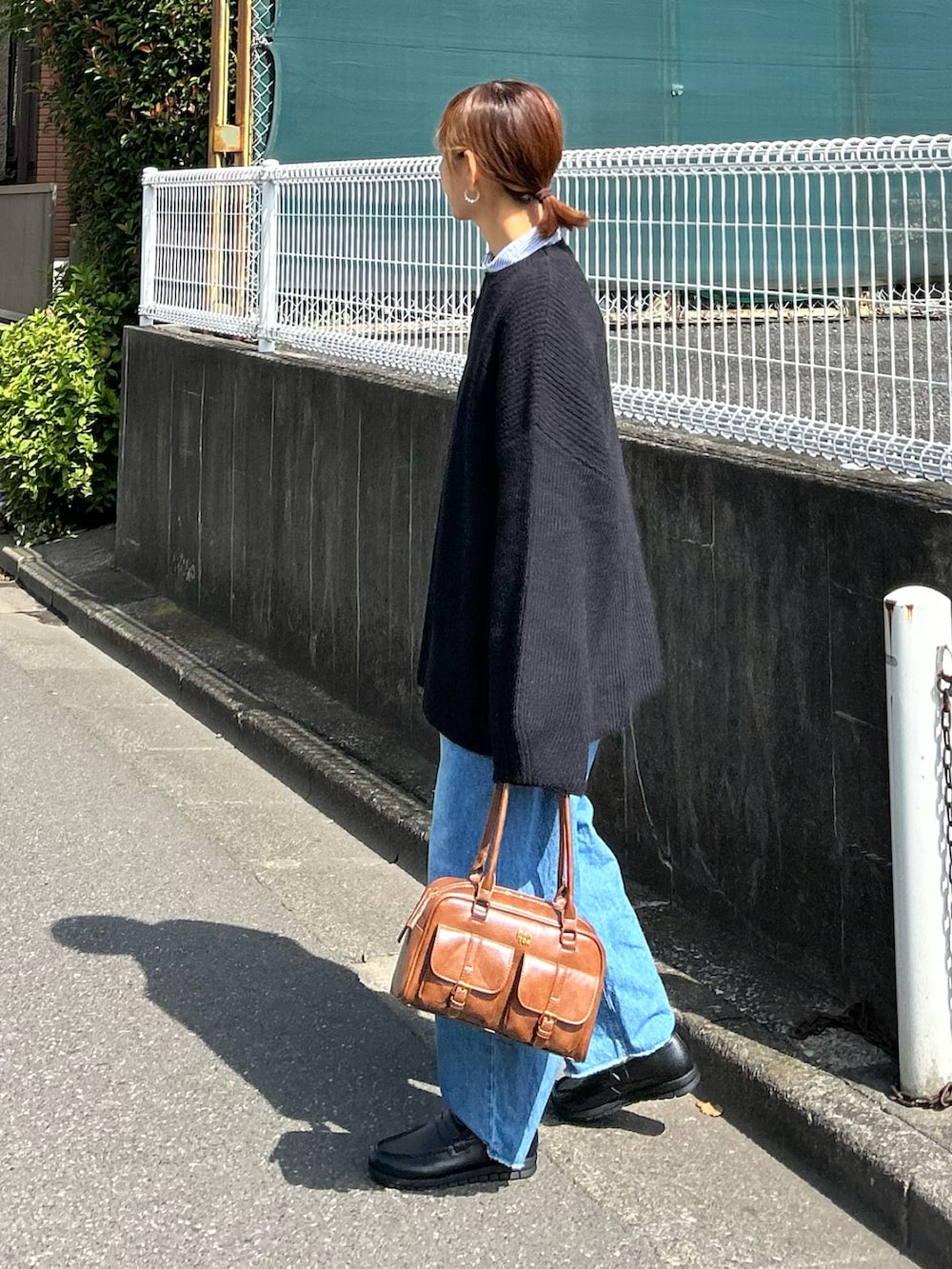 ブラック系のニット/セーター、ブルー系のデニムパンツ、ブラウン系のハンドバッグを着用したレディースの秋コーディネートの3枚目の写真