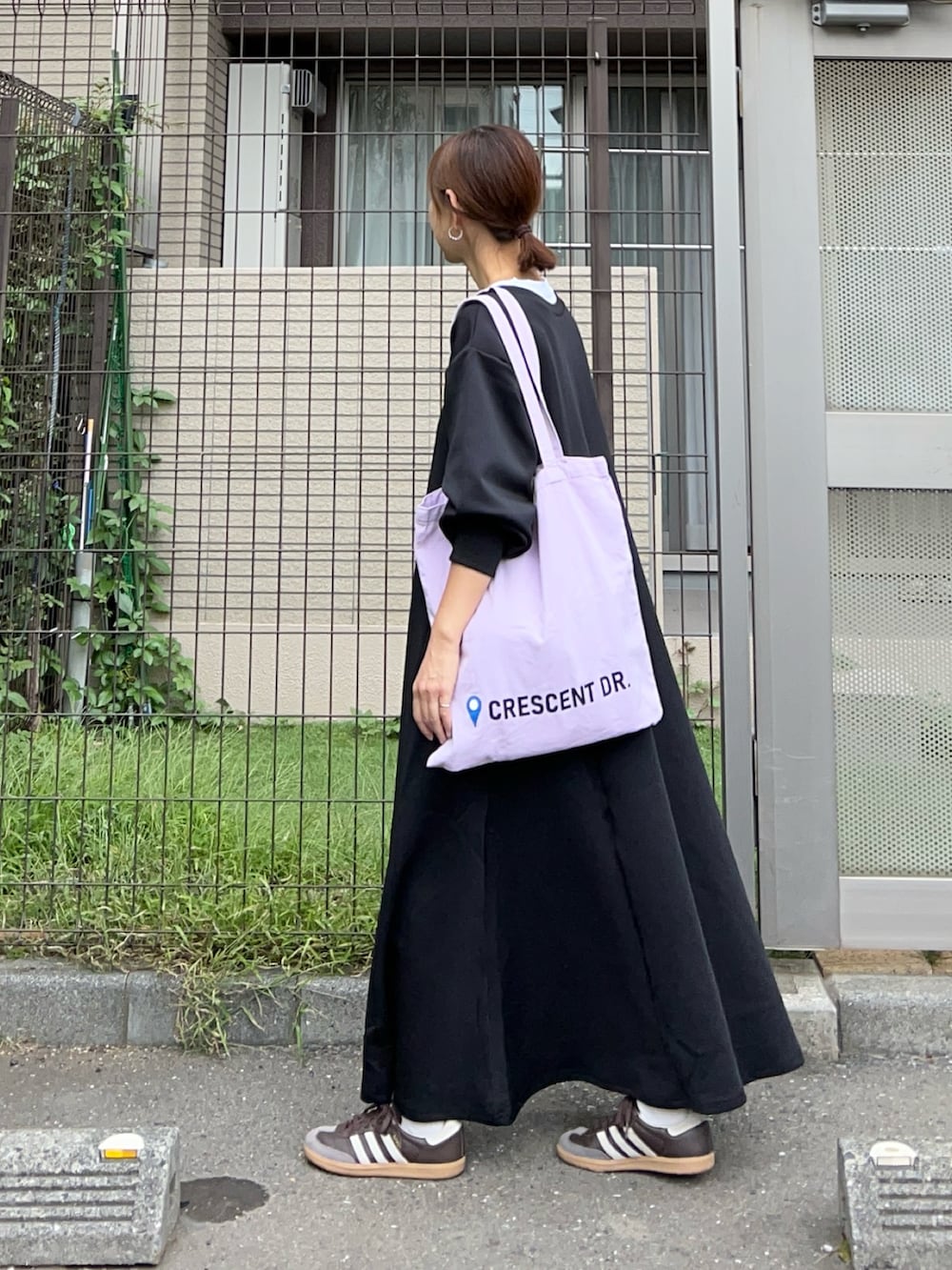 ブラック系のワンピース、オレンジ系のトートバッグ、ブラウン系のスニーカーを着用したレディースの秋コーディネートの3枚目の写真
