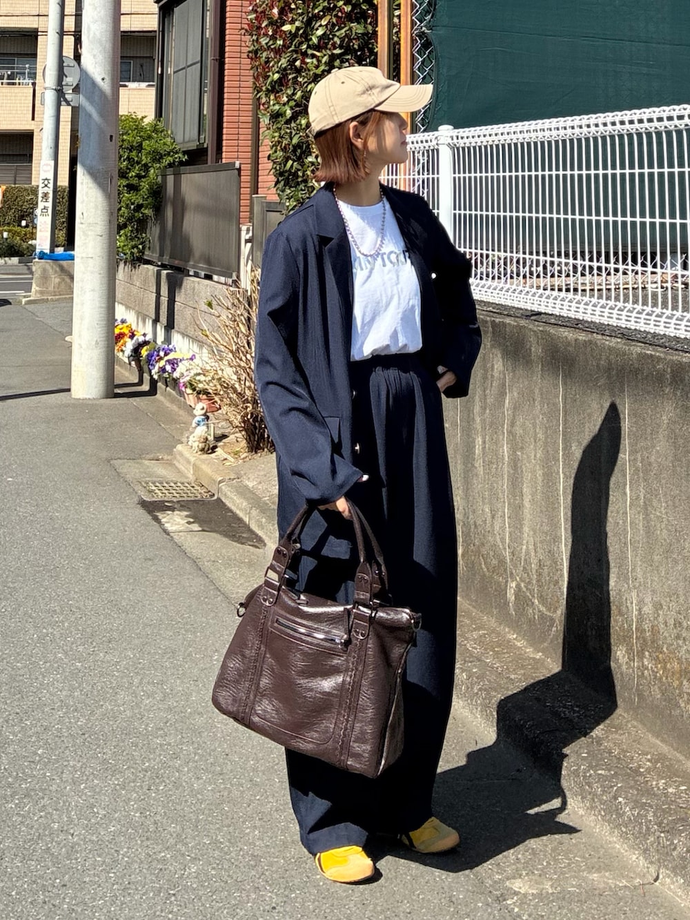 ブルー系のテーラードジャケット、ブルー系のスラックス、ブラウン系のトートバッグを着用したレディースの春コーディネートの2枚目の写真